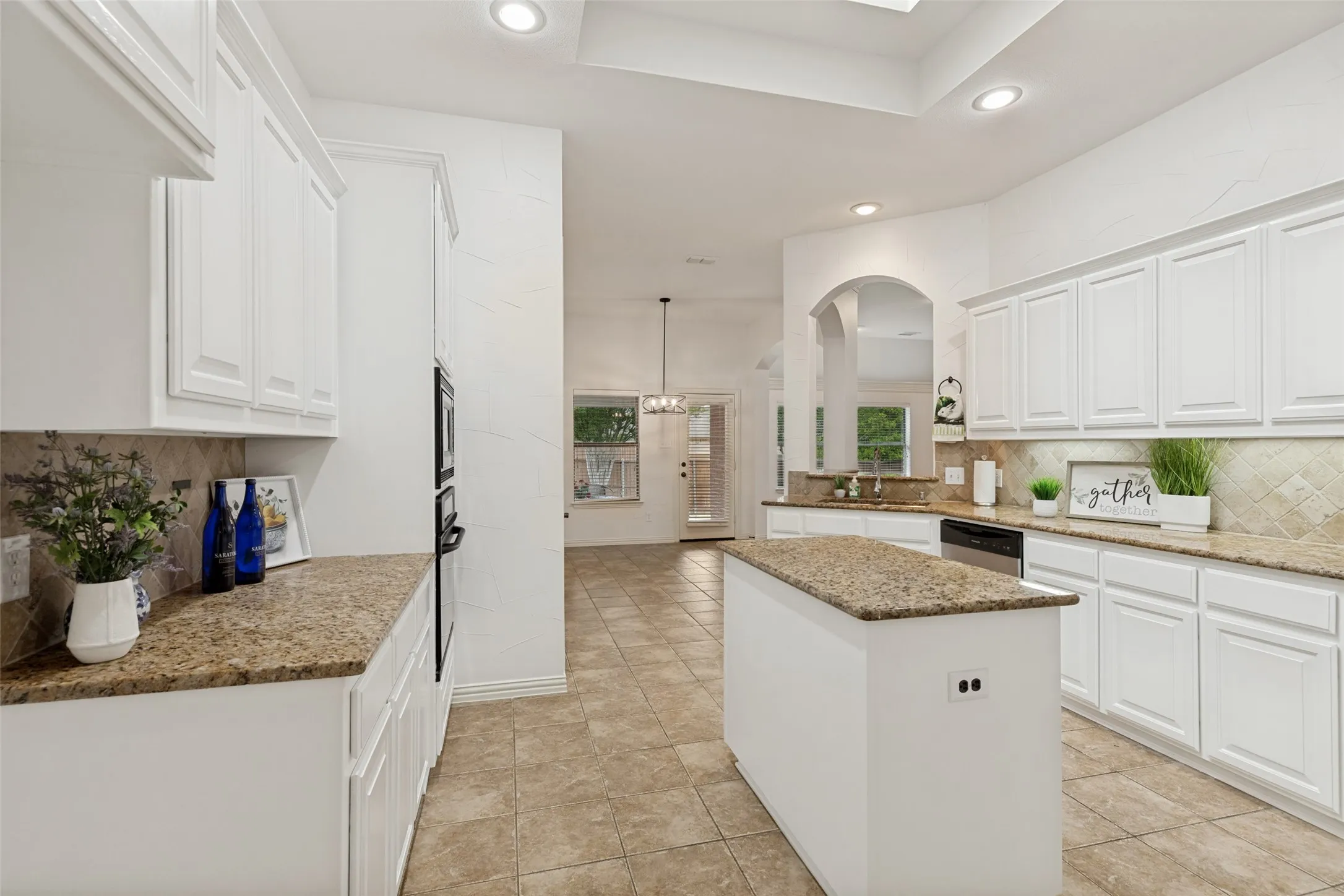 Contemporary kitchen featuring white cabinetry, granite countertops, tile flooring, recessed lighting, and a built-in oven