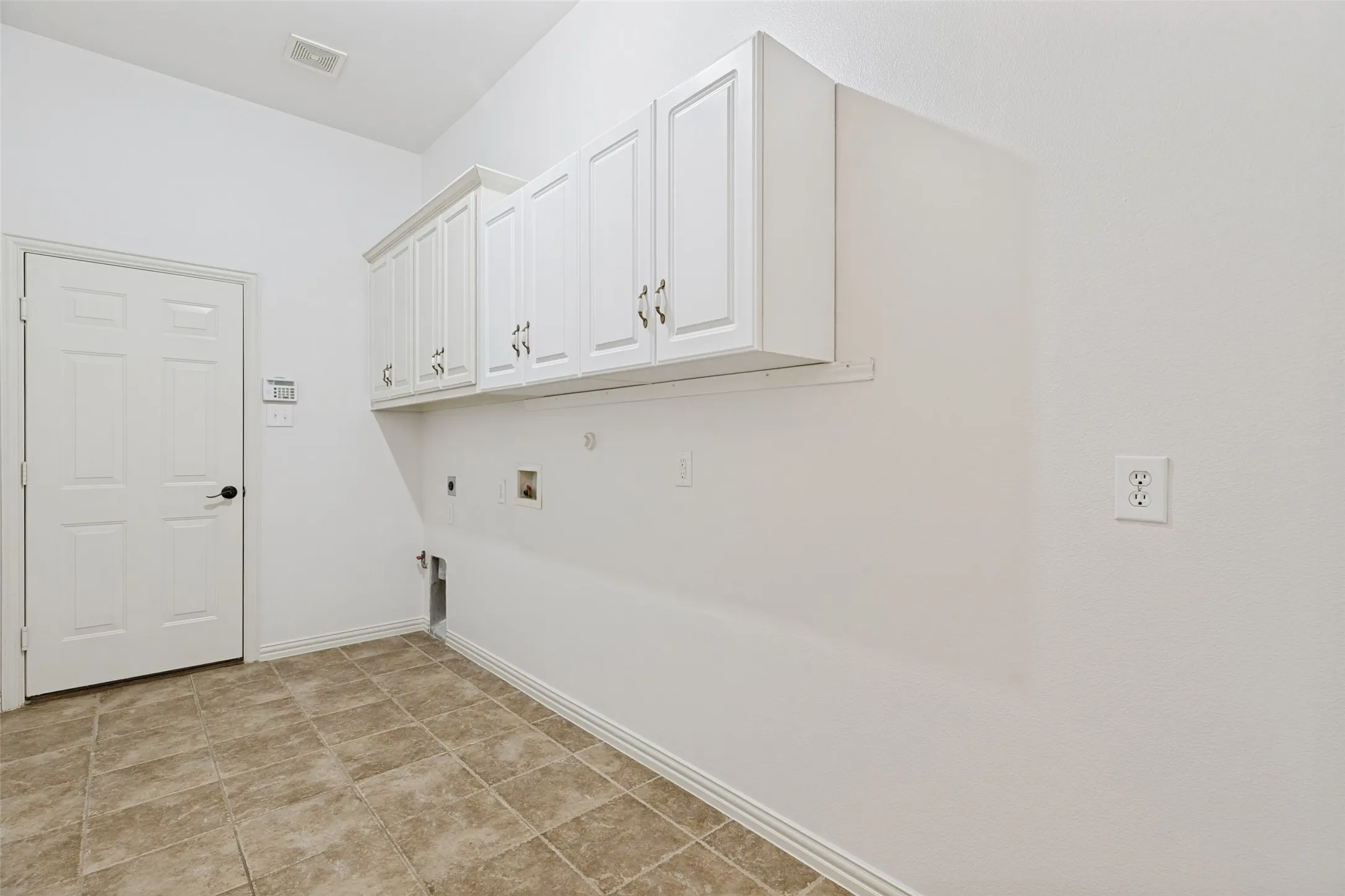 Utility room featuring a gas stub, tile flooring, white shaker-style cabinetry, and room for a freezer or refrigerator.