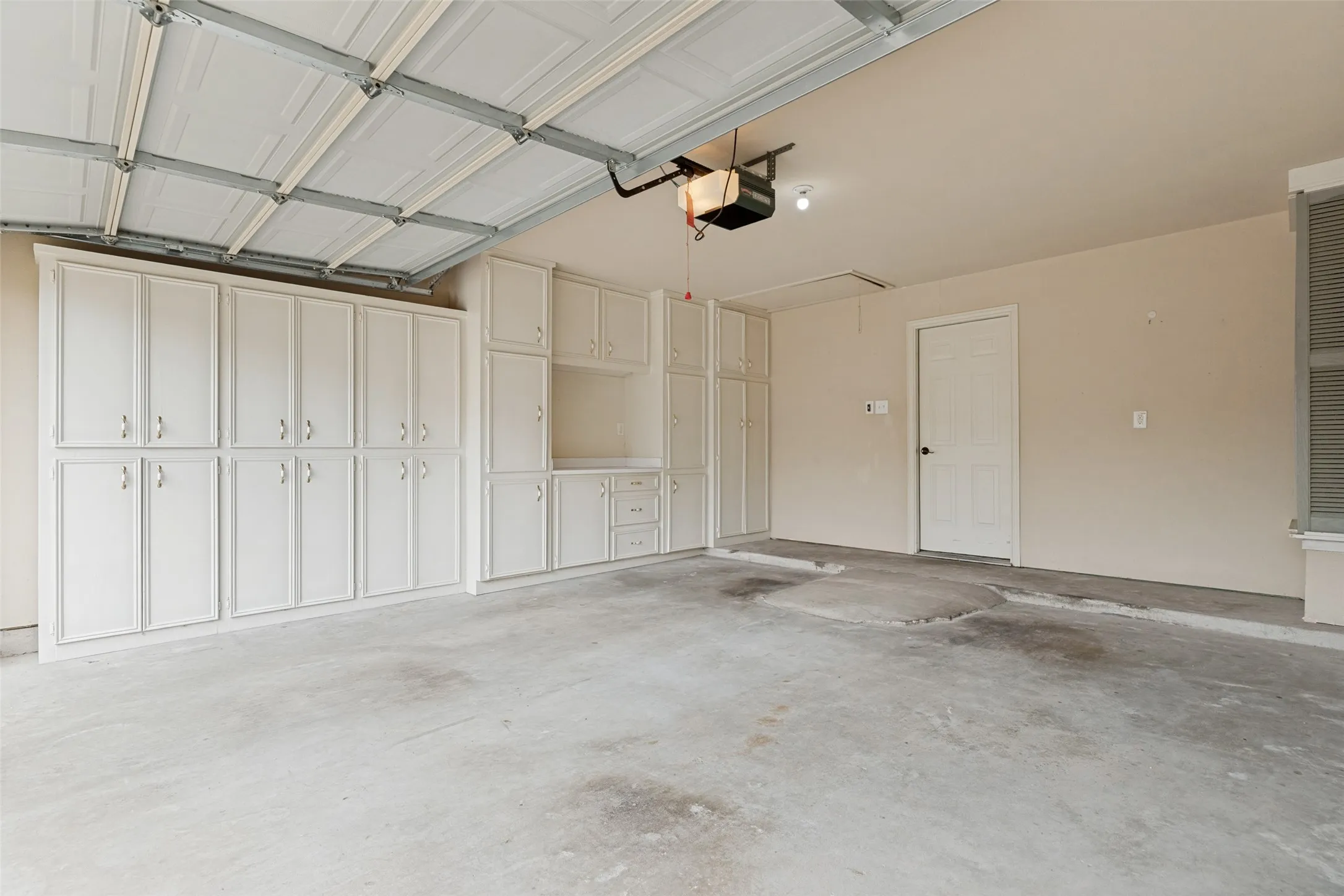 Fabulous storage area in the garage!! Extensive built-in white cabinets and drawers, an automatic garage door opener, and a louvered enclosure around the water heater.