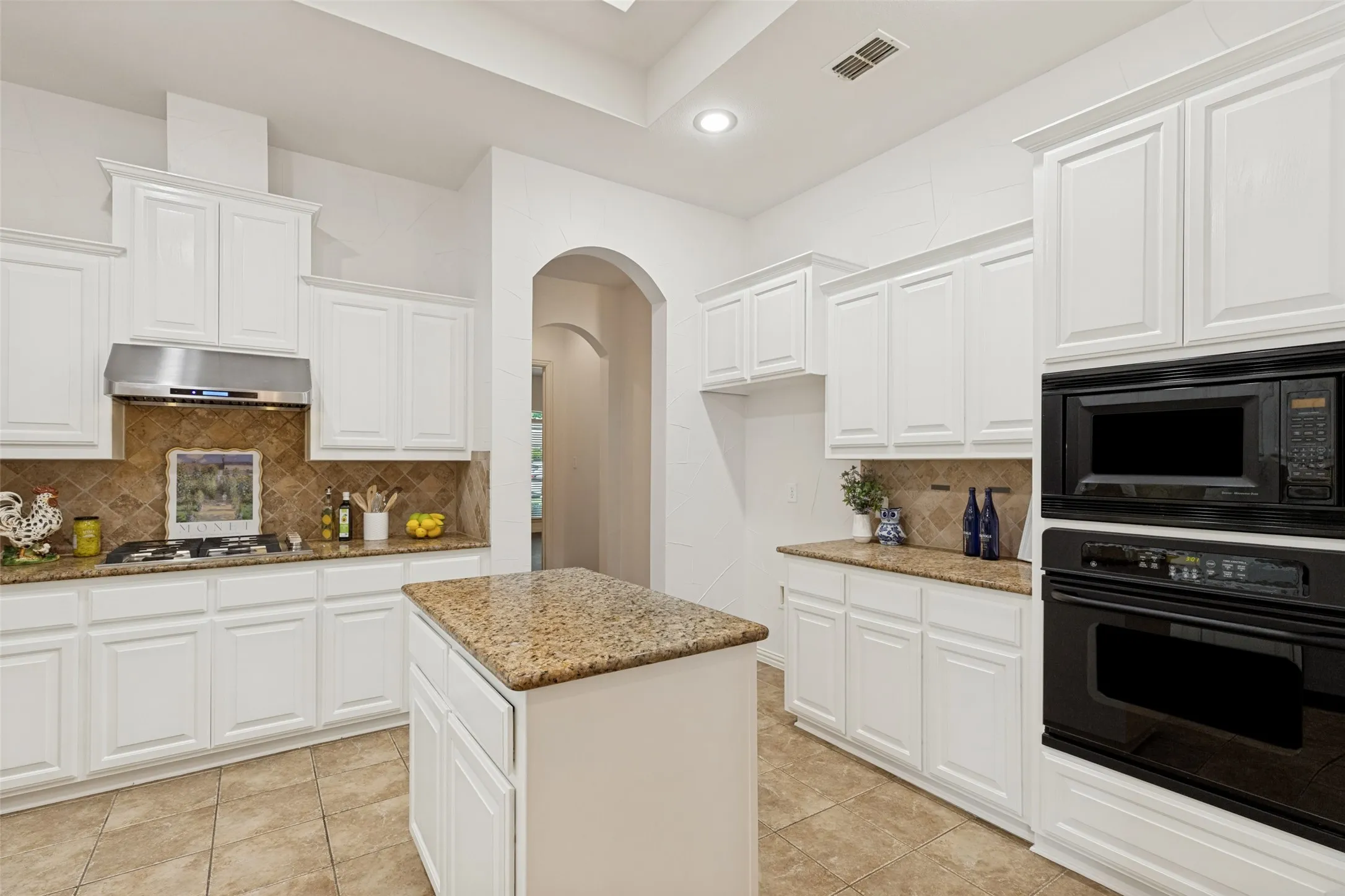 Kitchen featuring white cabinetry, granite countertops, a central island, stainless steel gas range, and built-in wall oven and microwave