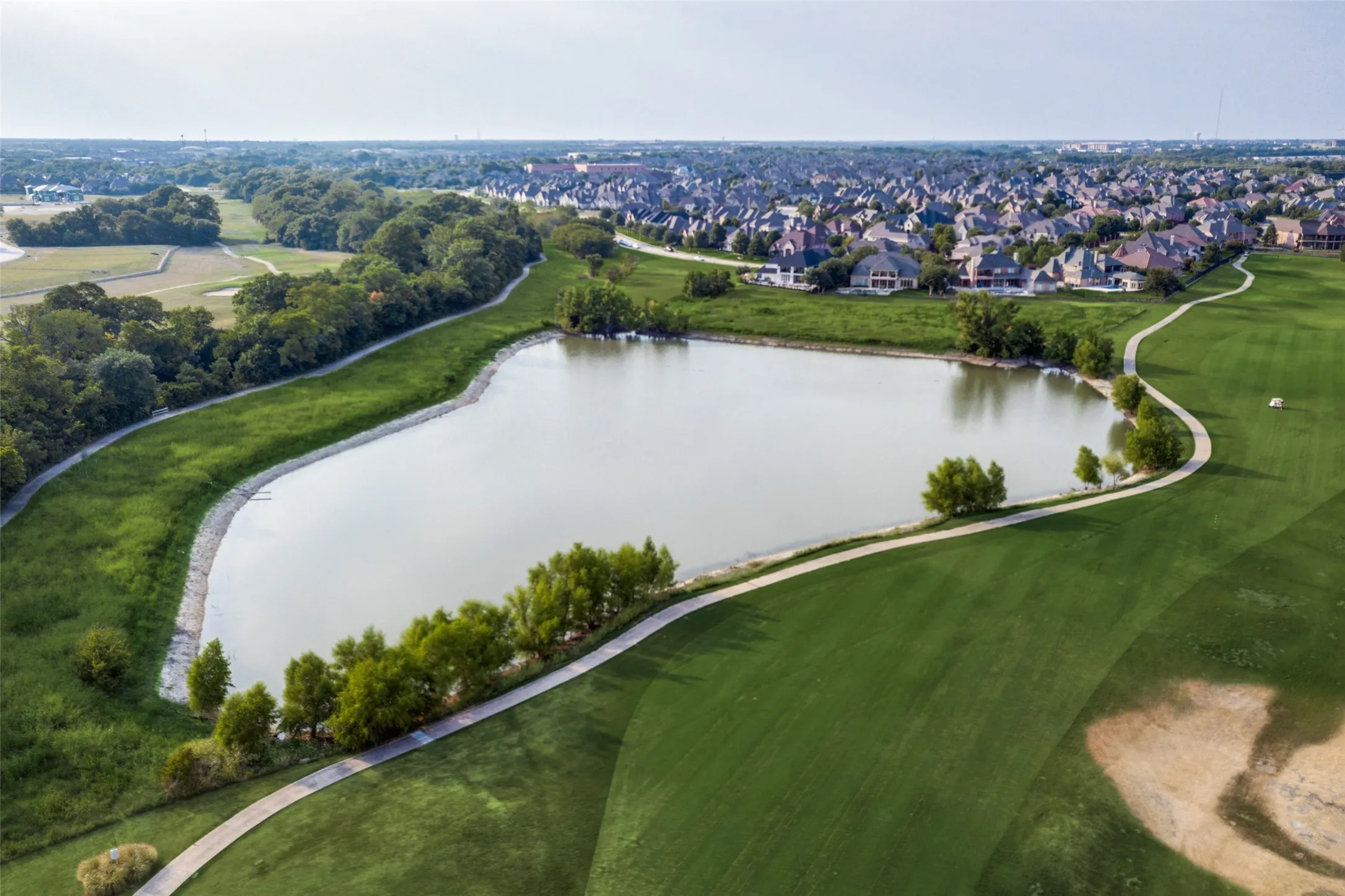 Expansive golf course view in Twin Creeks Master-Planned Community featuring a sizable pond with surrounding fairways.