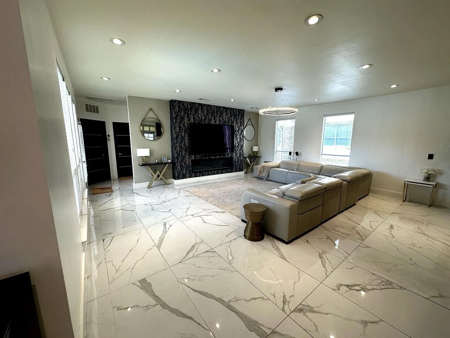 Spacious living area featuring large format marble-looktile flooring and rec essed lighting