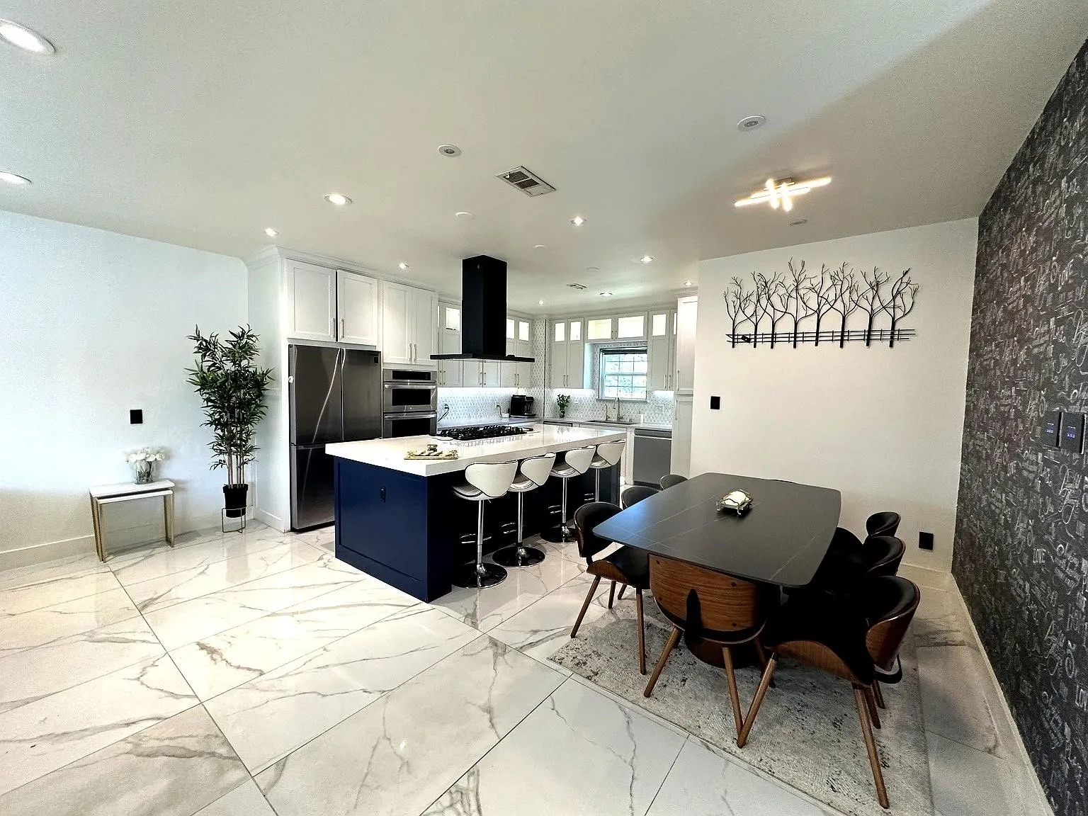Expansive kitchen featuring a large blue island with white countertop, stainless steel appliances, white cabinetry, and recessed lighting