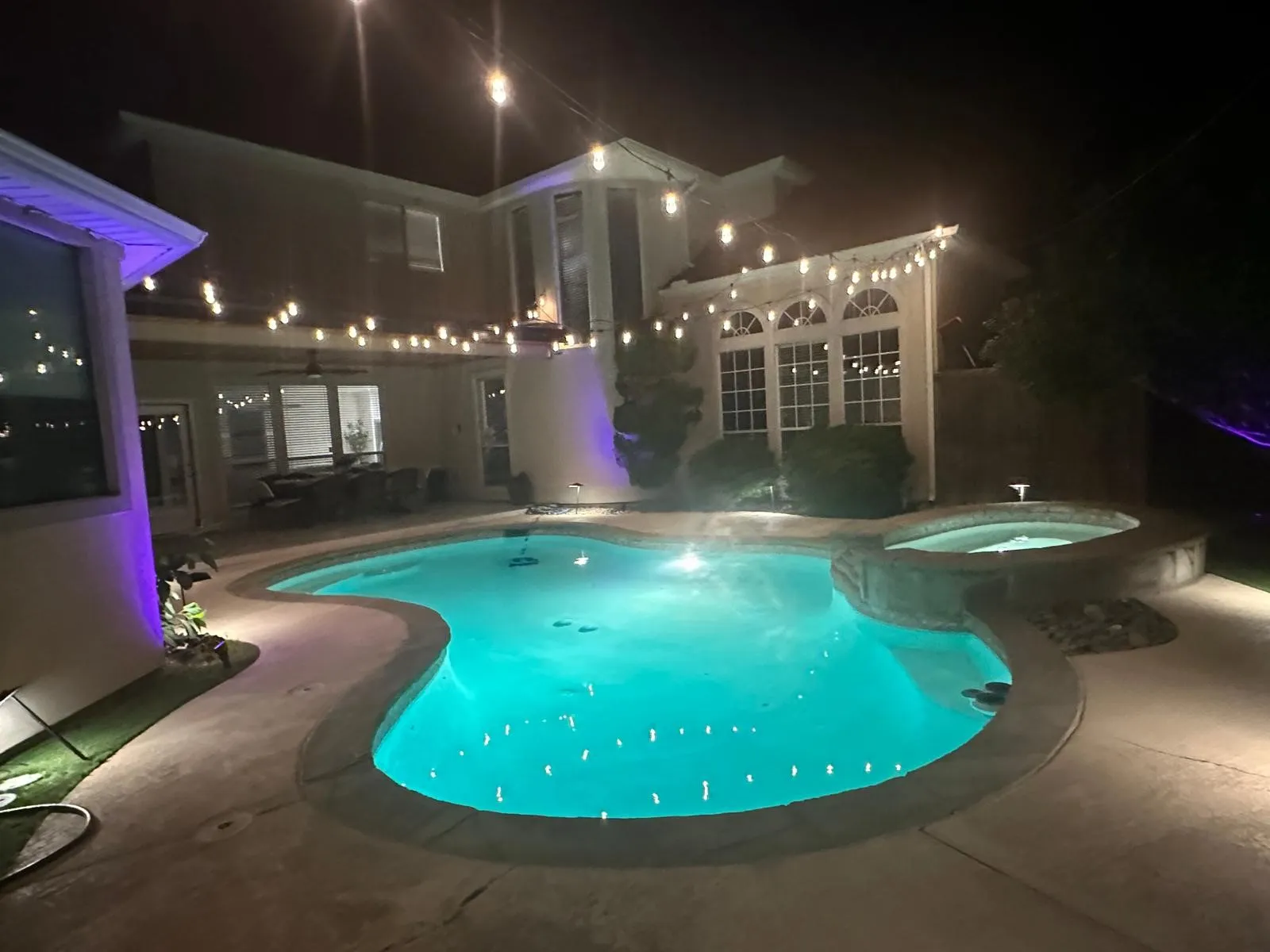Outdoor swimming pool with integrated spa and concrete decking