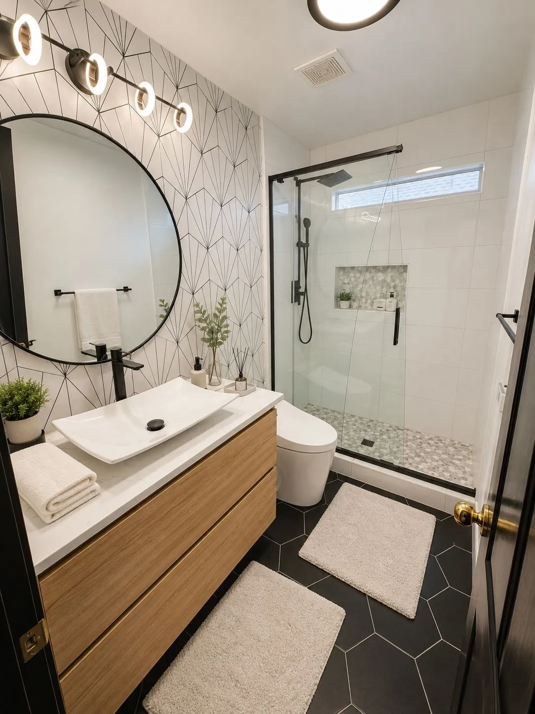 Bathroom featuring a floating wood-finish vanity with a vessel sink, a walk-in shower with glass enclosure, black hexagonal floor tiles, and a geometric accent wall
