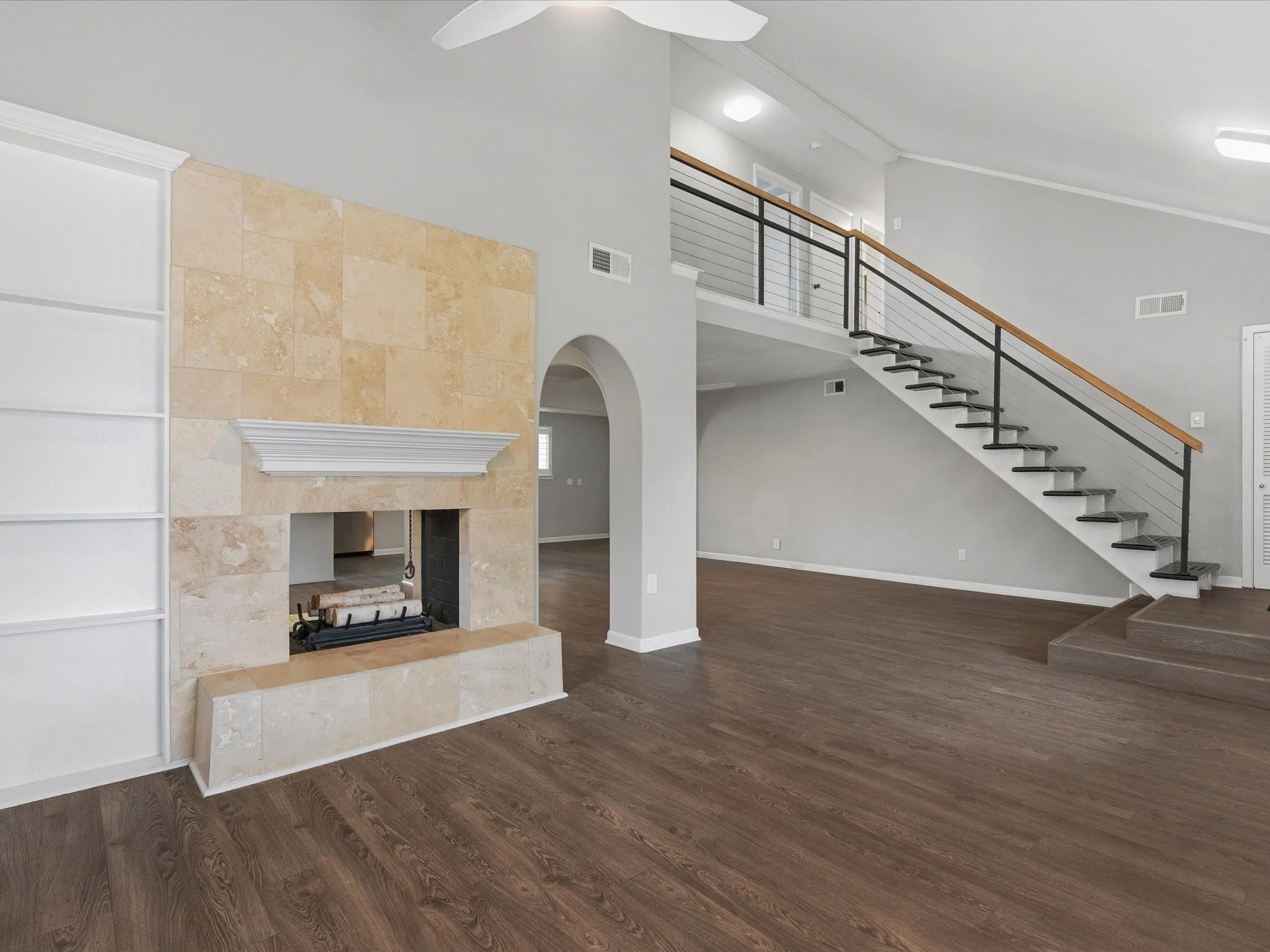 Living area featuring wood-finish flooring, a contemporary staircase with metal balusters and wood handrail, and a two-story ceiling