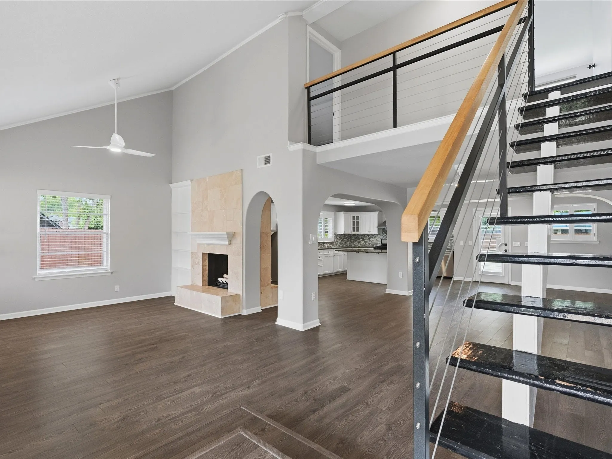Modern floating staircase with dark treads, cable railing, and a light wood-finish handrail