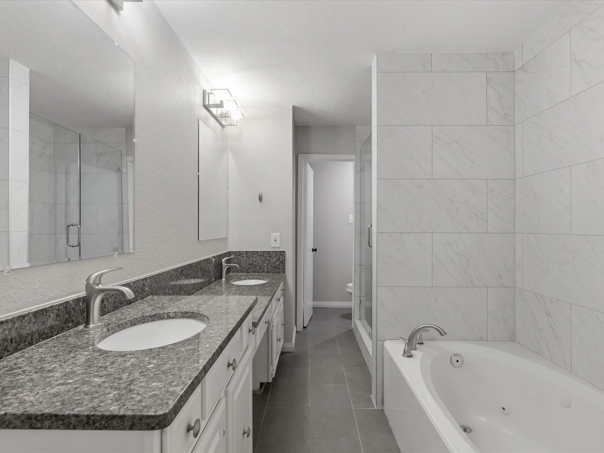 Bathroom featuring a dual vanity with granite countertops, undermount sinks, and brushed nickel fixtures