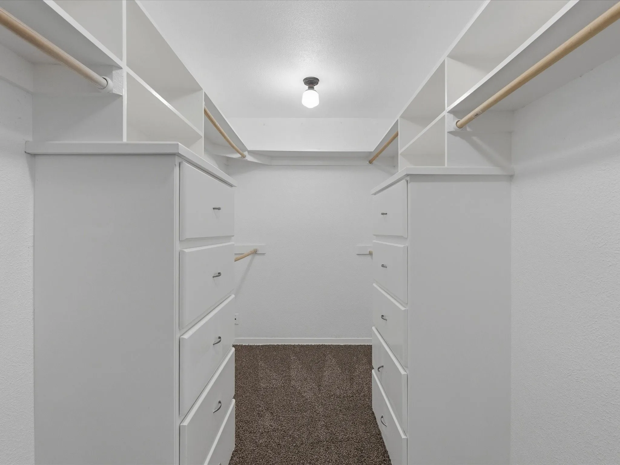 Walk-in closet with built-in white cabinetry, integrated shelving, and multiple hanging rods