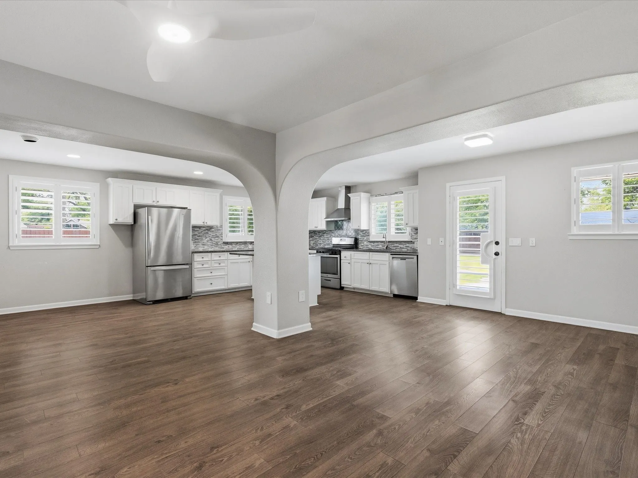 Wood-finish flooring throughout, complemented by a white kitchen featuring stainless steel appliances