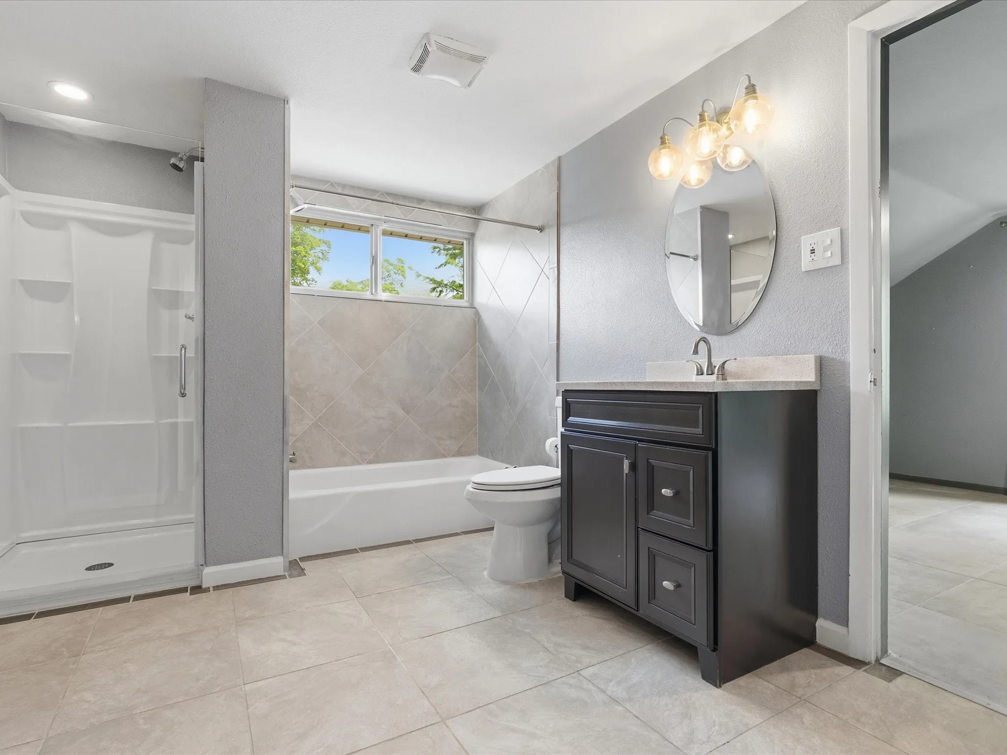 Bathroom featuring a dark wood-finish vanity with a light countertop, an oval mirror, and a three-light fixture