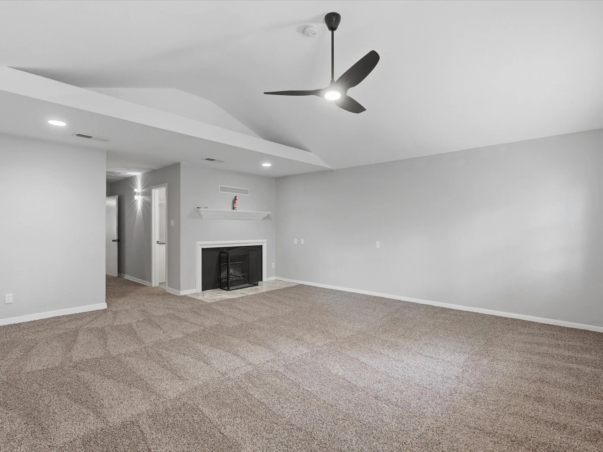 Spacious interior room featuring a vaulted ceiling and recessed lighting
