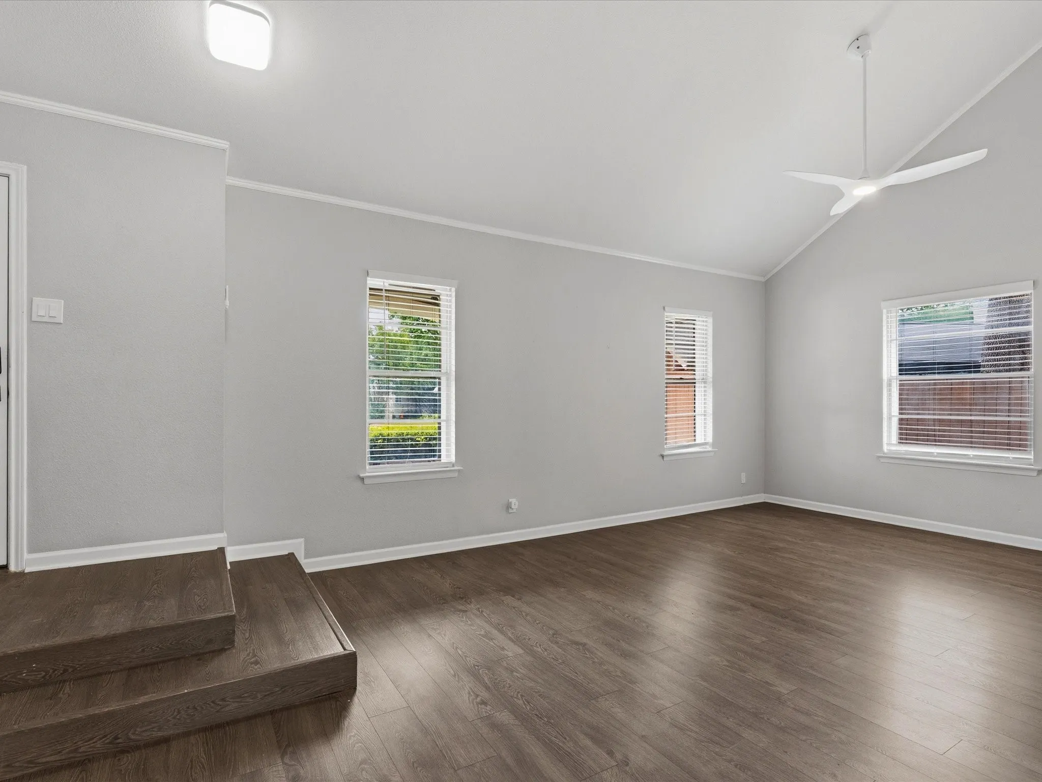 Spacious room featuring wood-finish flooring and a contemporary ceiling fan