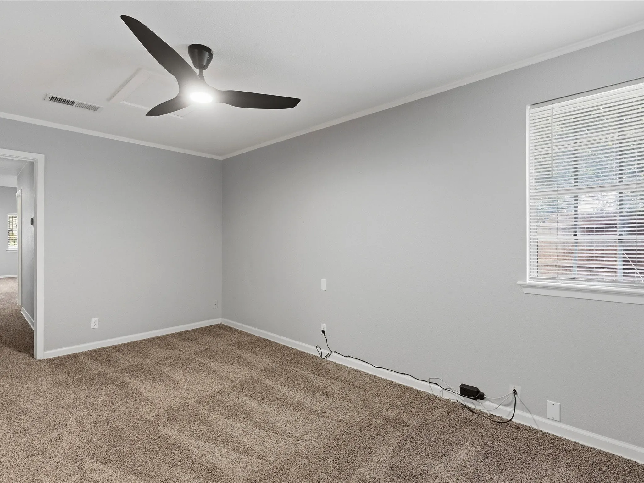 Carpeted room with light gray walls, a modern ceiling fan with integrated lighting, and a window featuring horizontal blinds