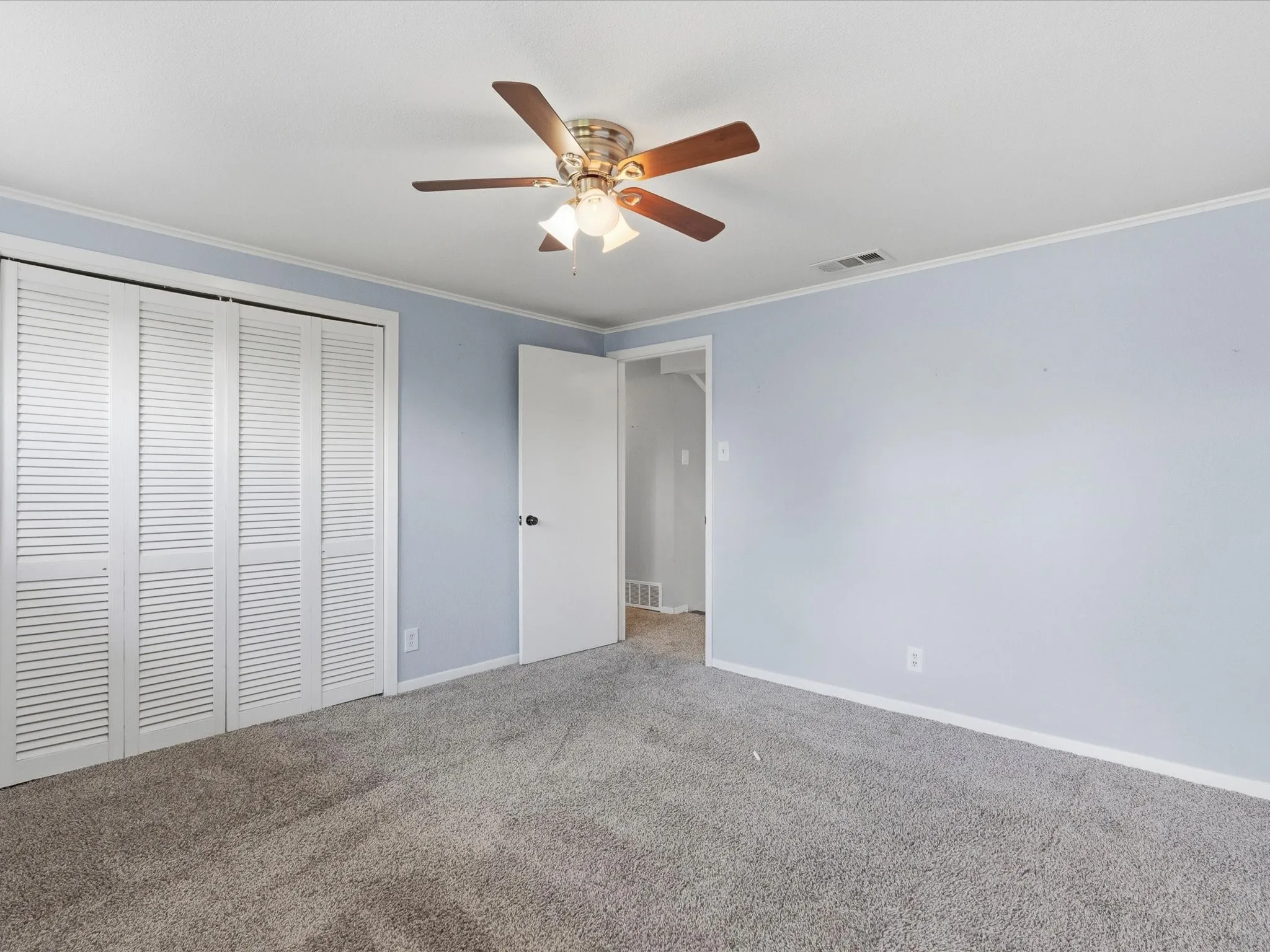 Carpeted room featuring light blue walls, white trim, and a ceiling fan with integrated lighting