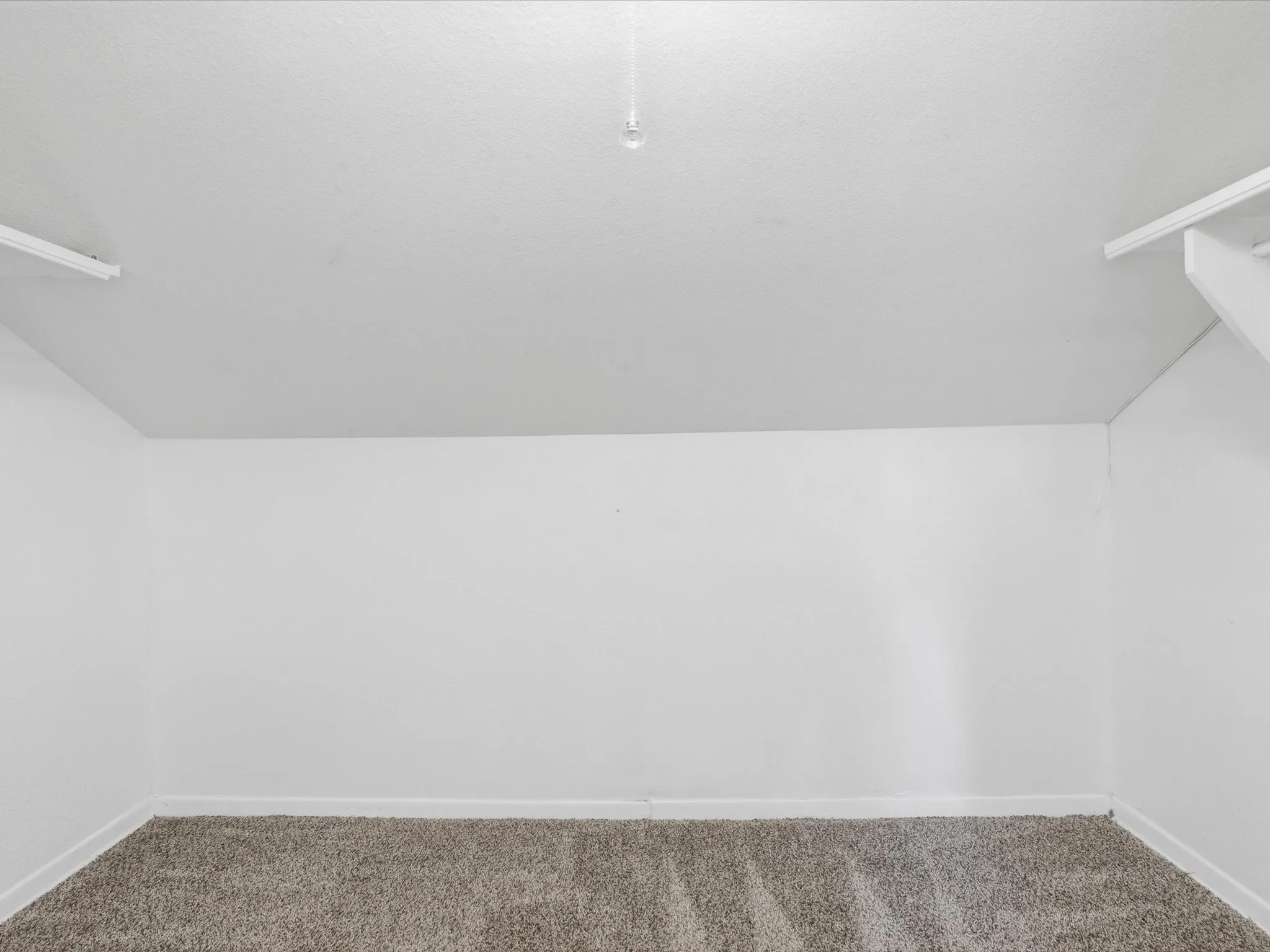 Neutral wall paint, textured ceiling, light fixture, and plush carpeting