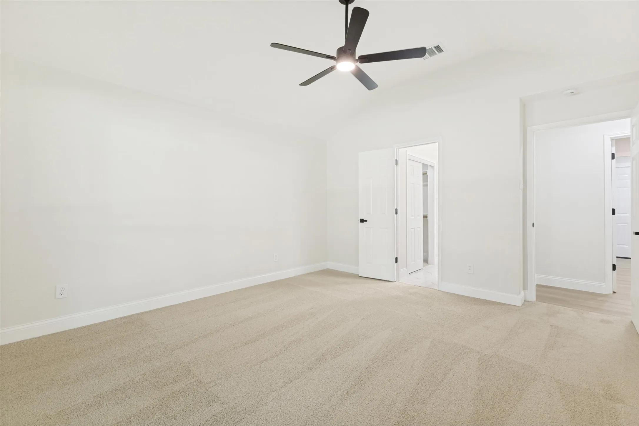 Neutral-toned carpet flooring and white baseboards