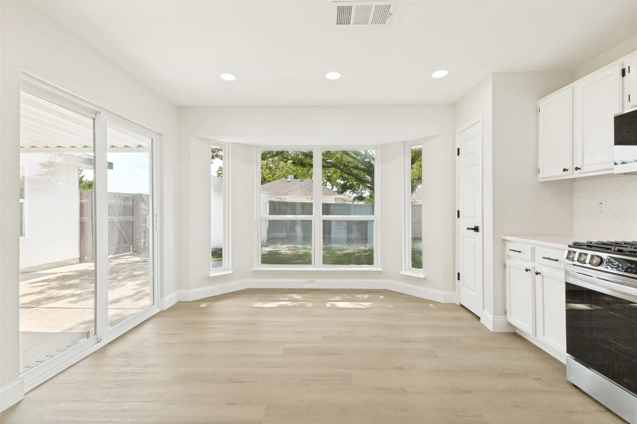 Bright interior space with light wood-finish flooring, recessed lighting, and a bay window