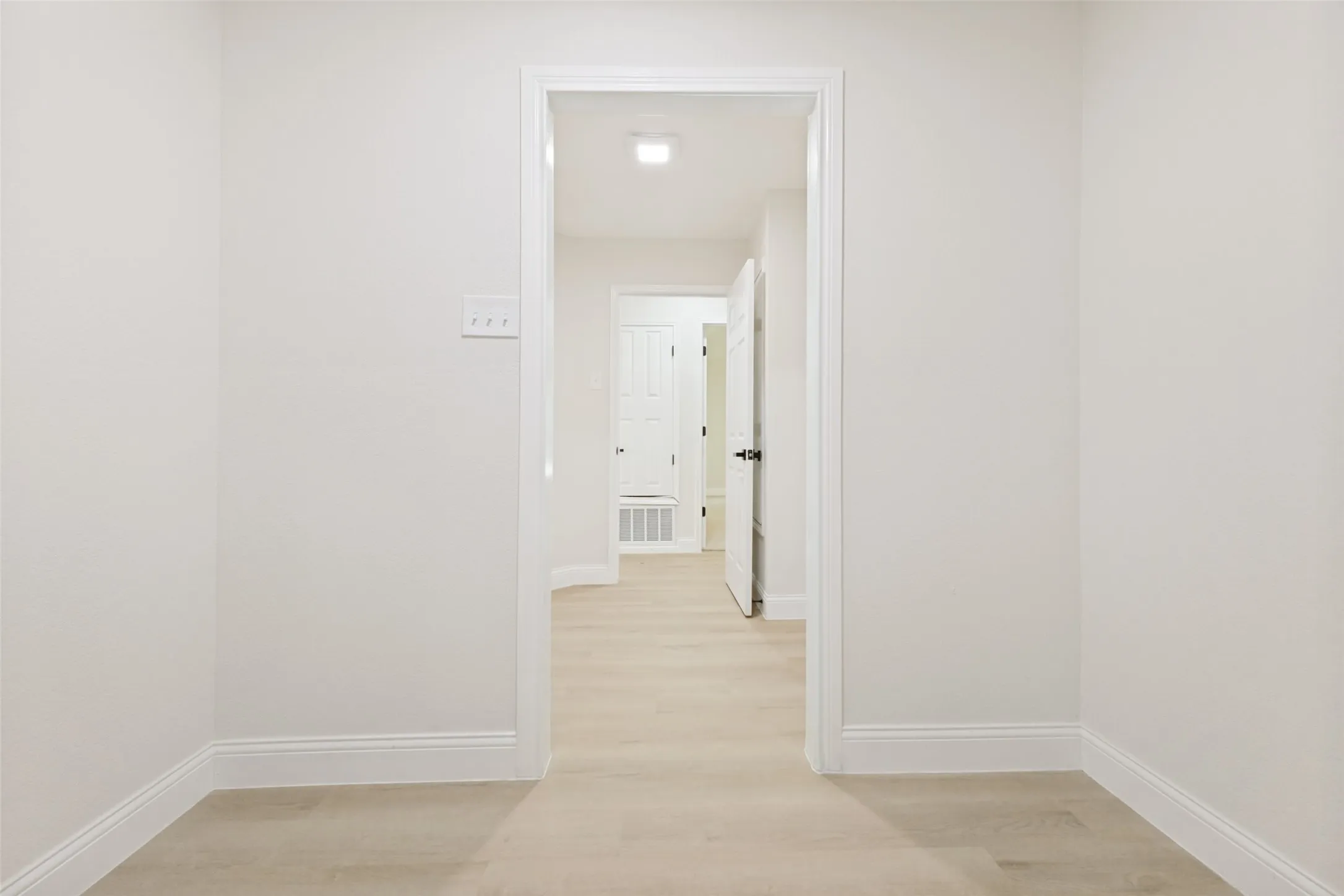 Hallway featuring light wood-finish flooring, white walls, and white baseboards