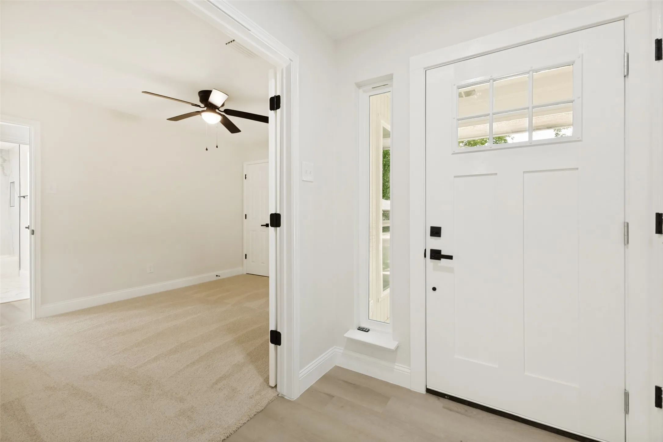 Entryway featuring a white craftsman-style door with a multi-pane window and matte black hardware