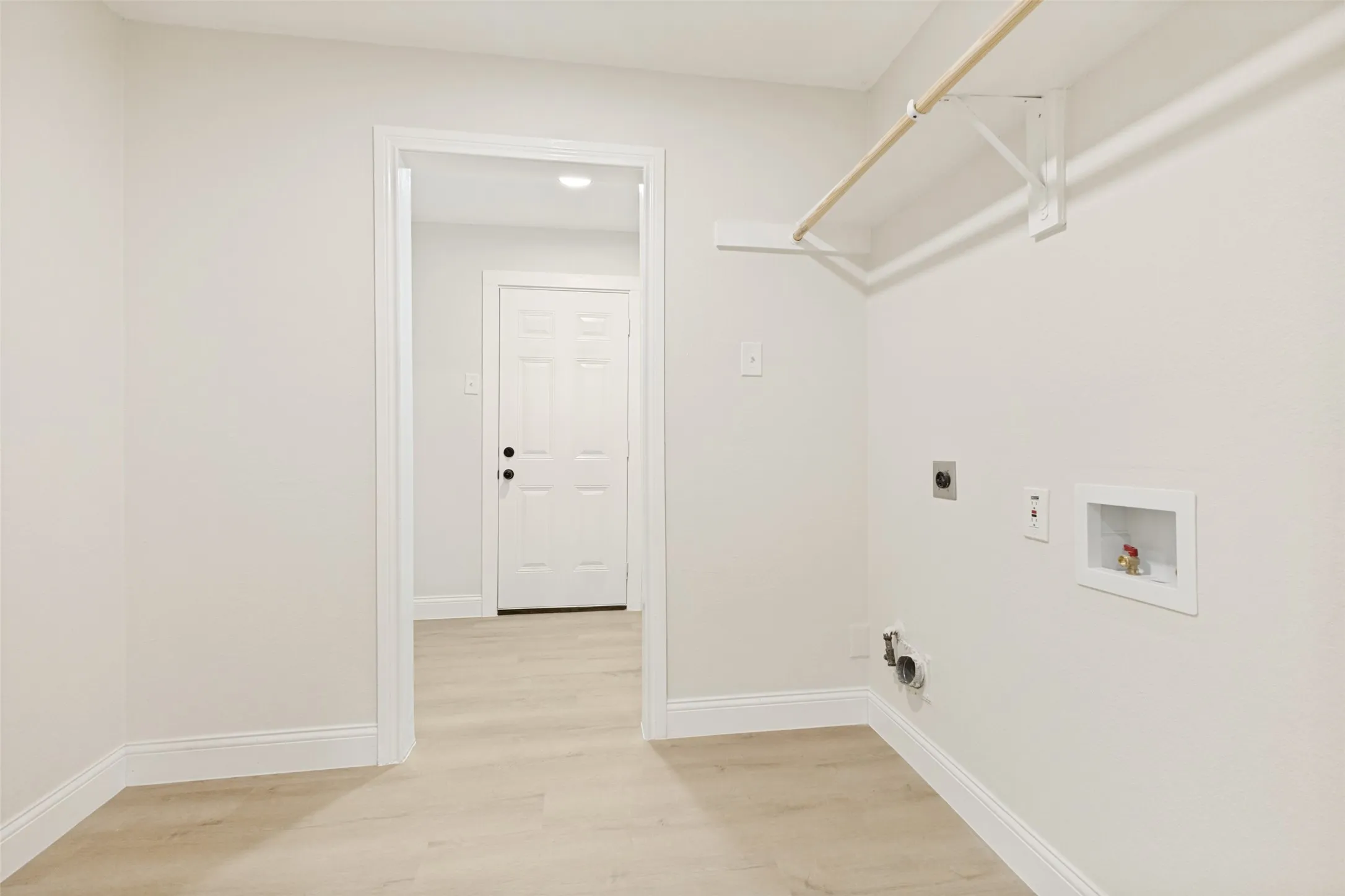 Dedicated laundry area featuring a light wood-finish flooring and a neutral color palette