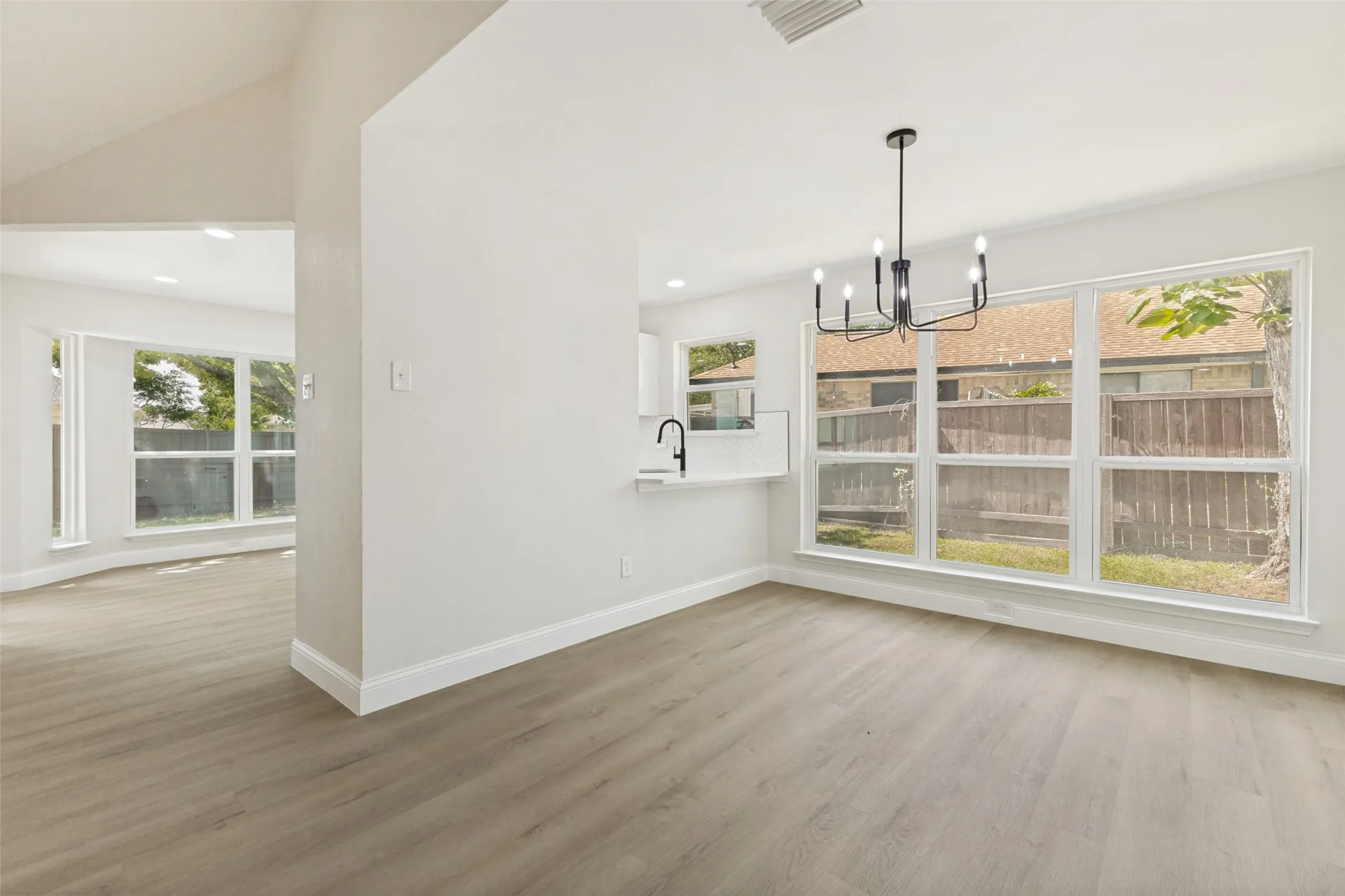 Spacious interior featuring light wood-finish flooring and a contemporary black chandelier