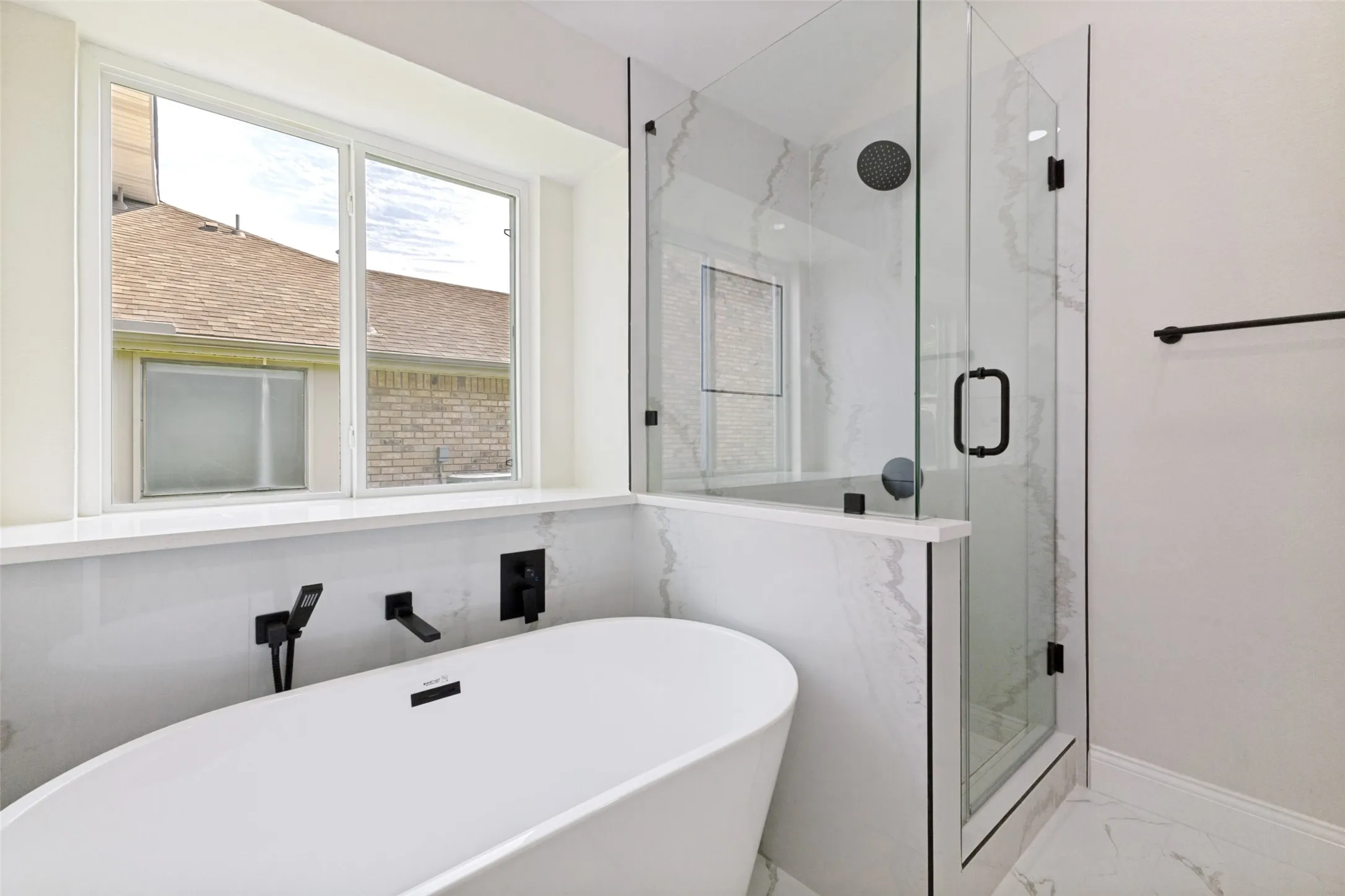 Freestanding soaking tub with wall-mounted matte black fixtures