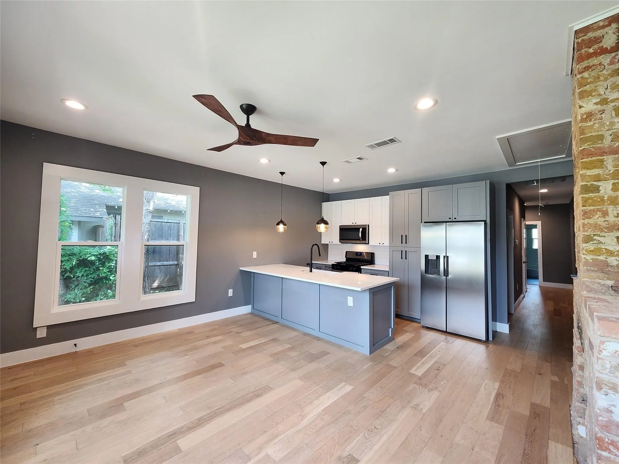 Kitchen and living area featuring light wood-finish flooring, recessed lighting, and a modern ceiling fan