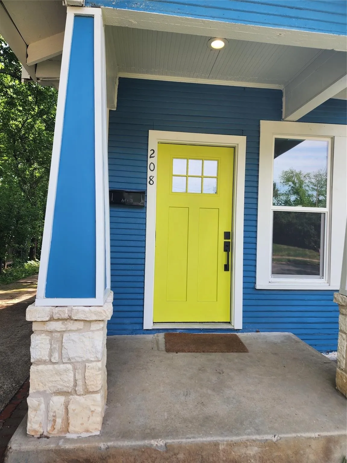 Vibrant yellow paneled door with upper glass inserts, set against blue horizontal siding