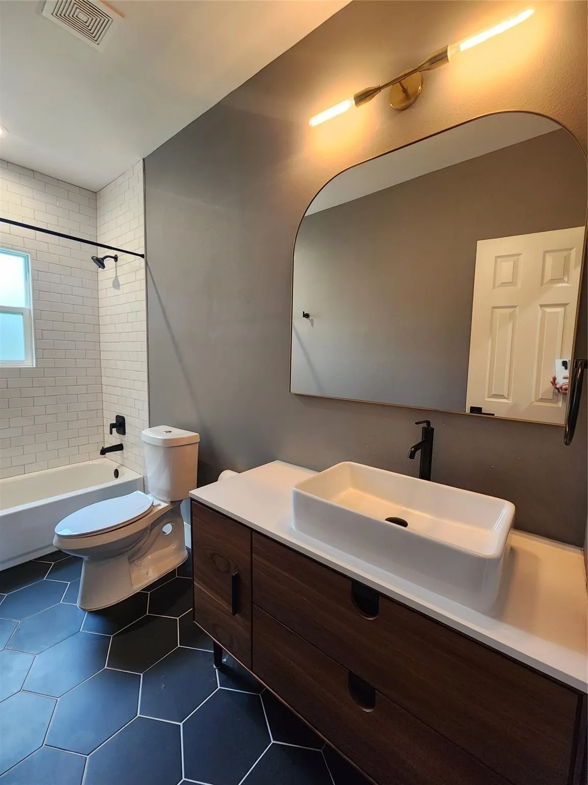 Modern bathroom featuring a wood-finish vanity with a rectangular vessel sink and matte black faucet