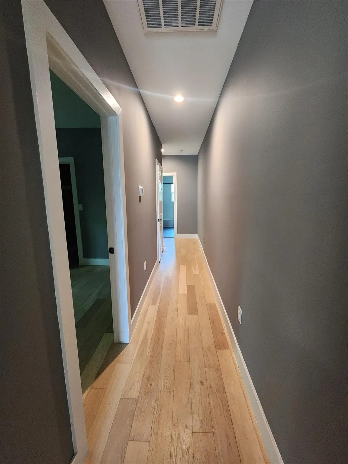 Hallway featuring wood-finish flooring, recessed lighting, white baseboards, and neutral wall paint
