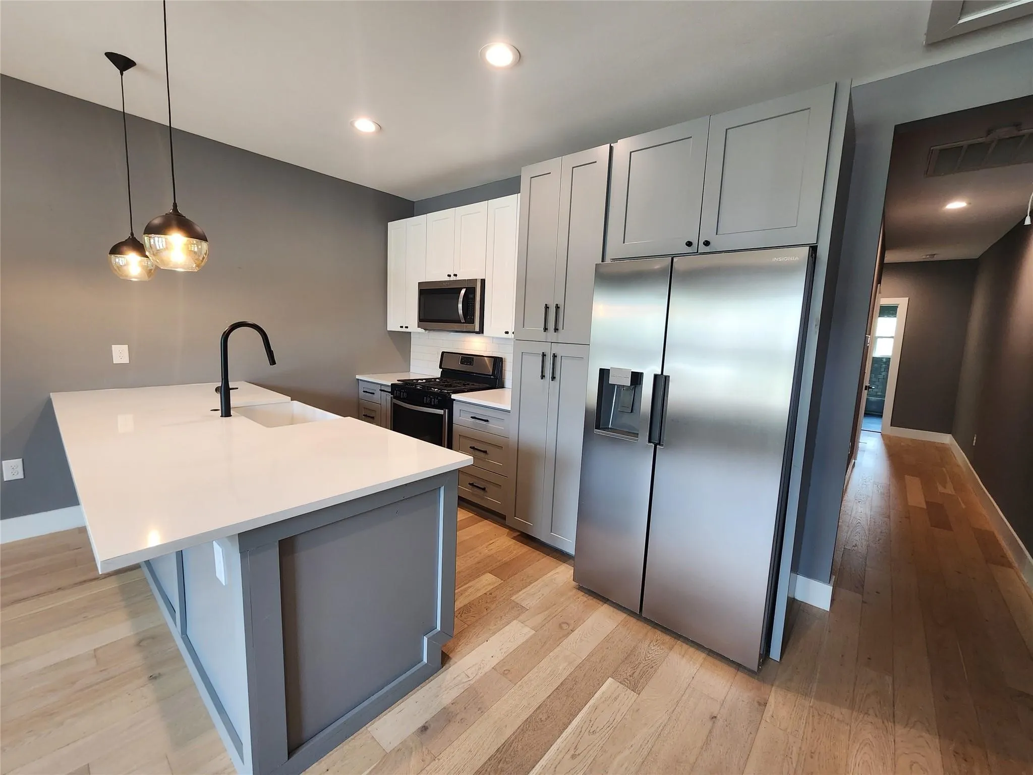 Modern kitchen featuring a large central island with a white countertop and integrated sink