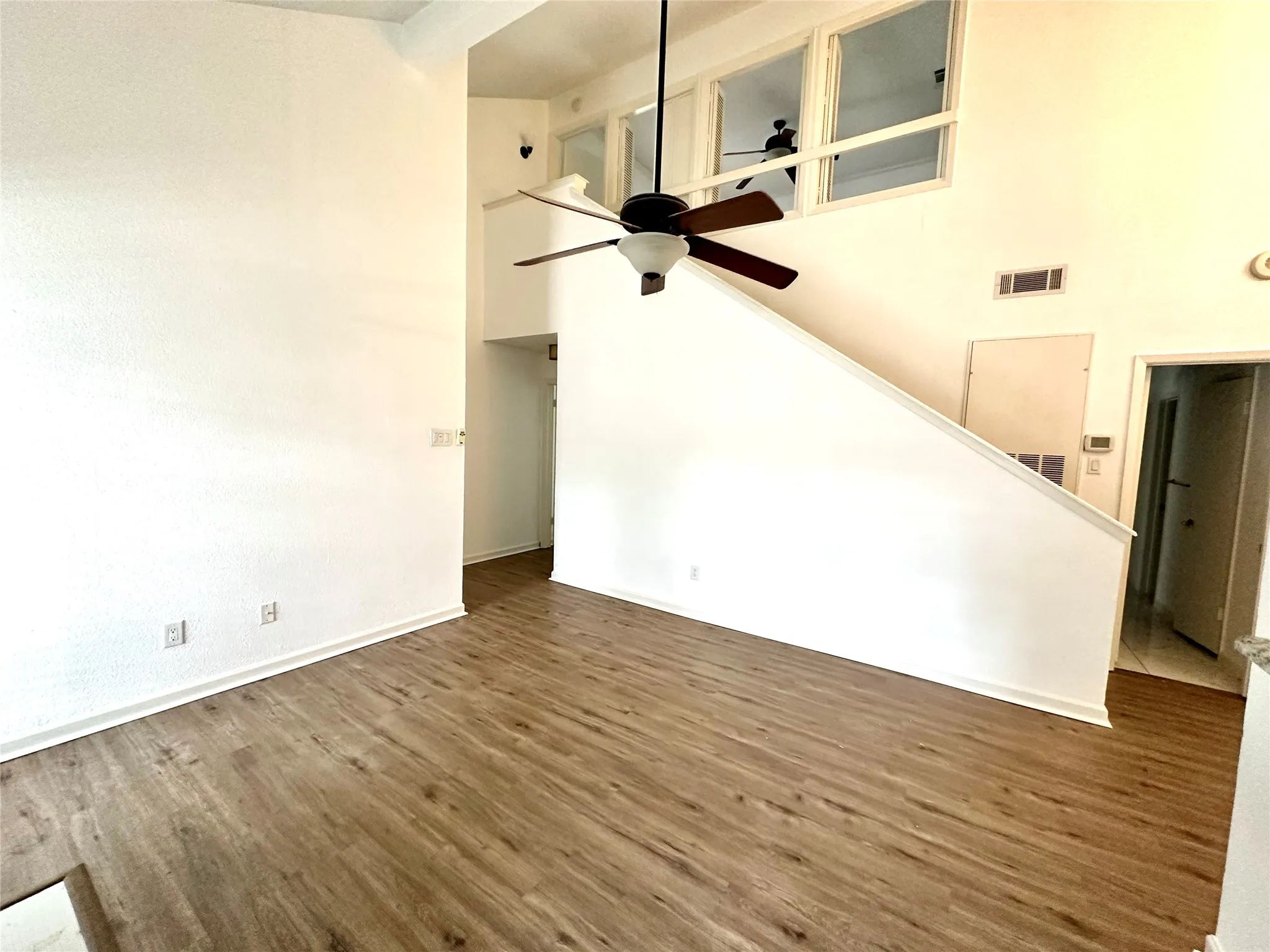 Living room featuring ceiling fan, hardwood / wood-style flooring, and a high ceiling