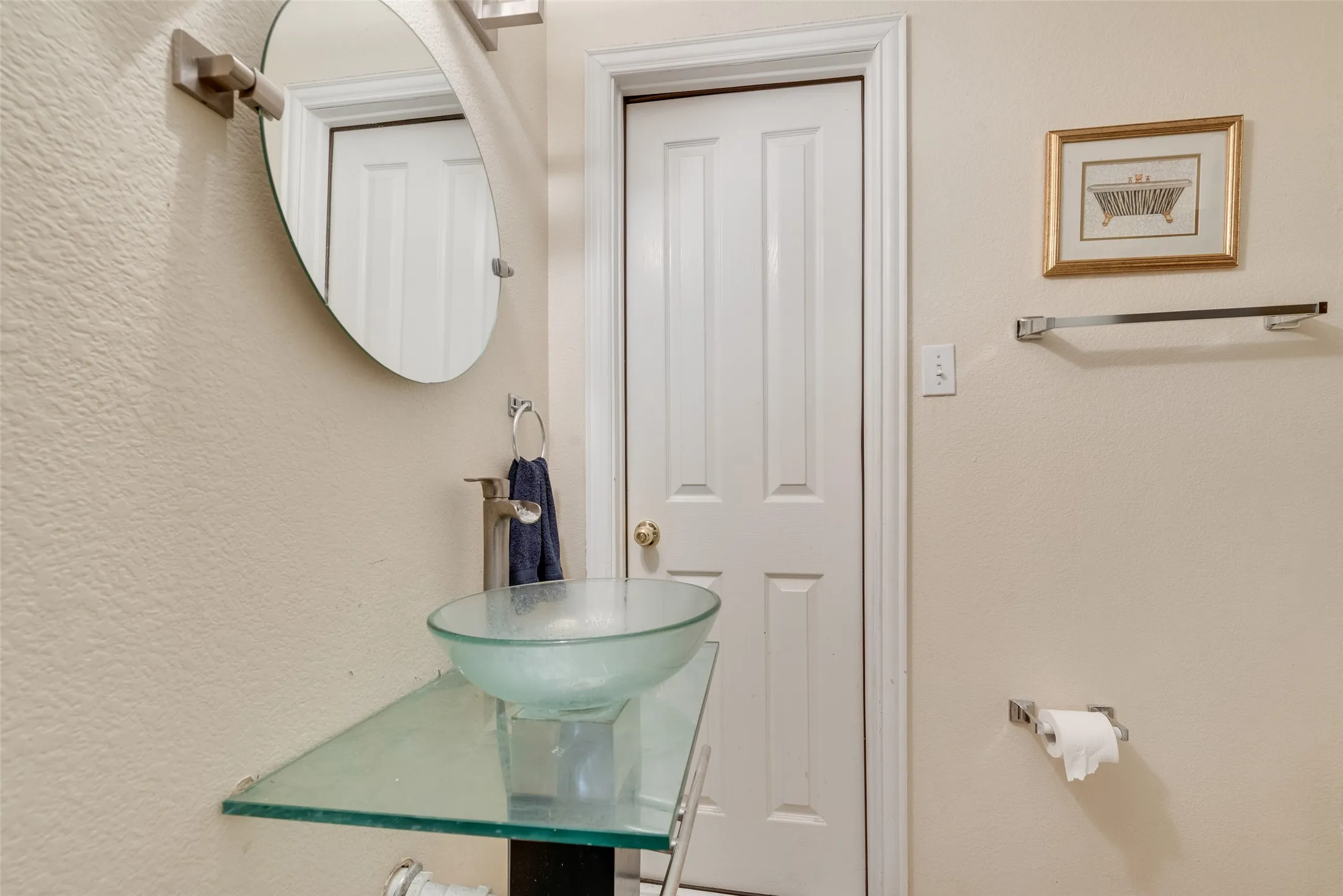 Vanity featuring a glass vessel sink, sleek chrome faucet, and glass countertop