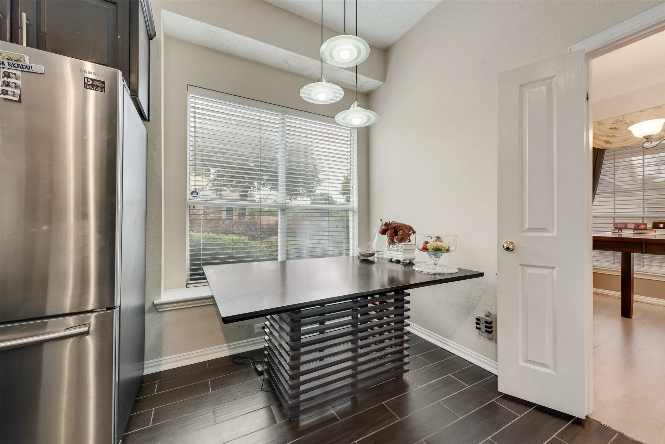 Kitchen dining area featuring wood-finish flooring, a large window with blinds, and pendant lighting