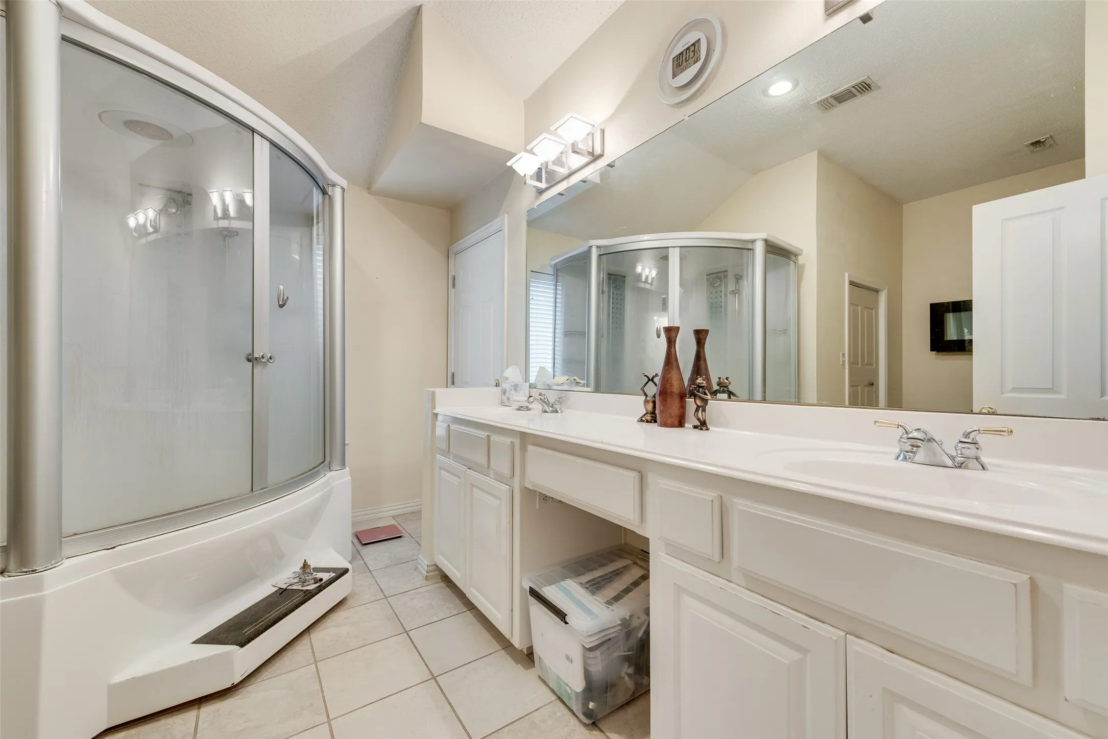 Dual vanity with integrated sinks, framed by a large mirror and overhead lighting fixtures
