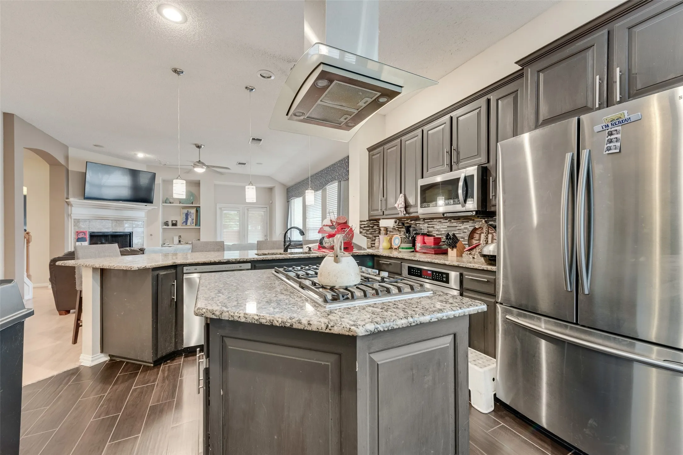 Modern kitchen featuring a central island with a gas cooktop, granite countertops, and dark wood cabinetry