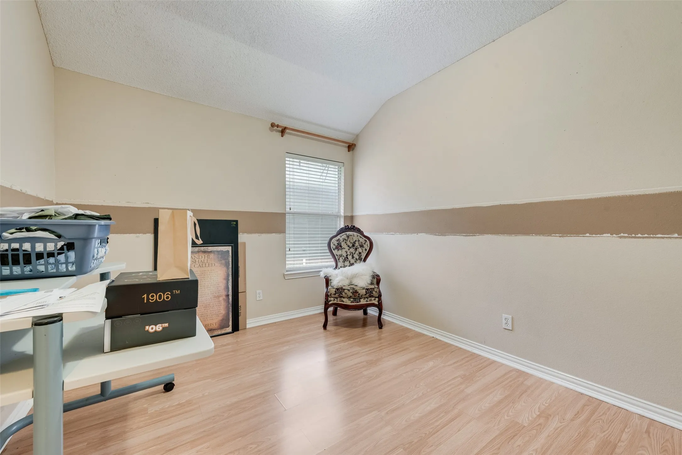 Room featuring light wood-finish flooring, a window with horizontal blinds, and a neutral wall color with a contrasting horizontal stripe