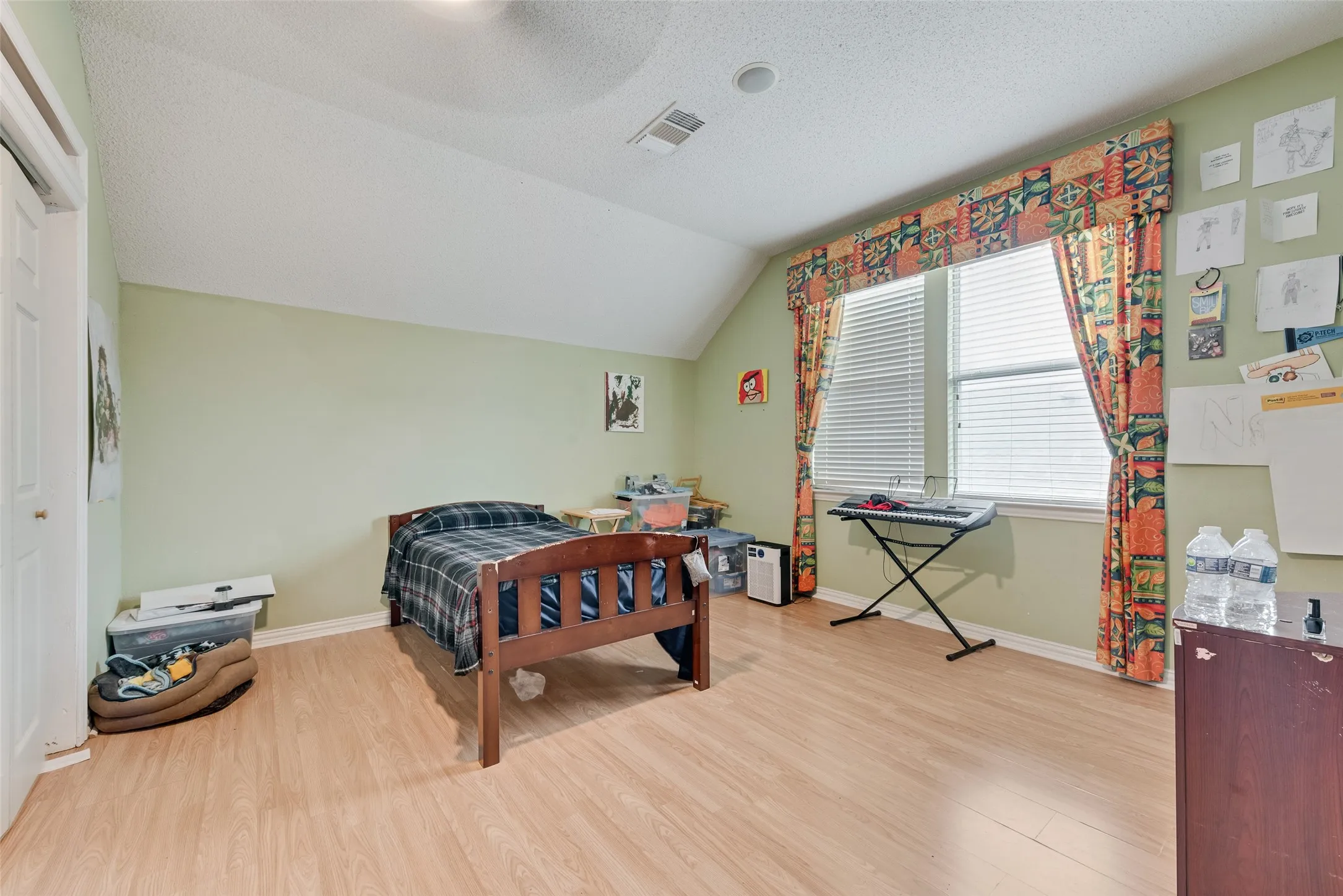 Spacious room featuring light wood-finish flooring and a vaulted ceiling
