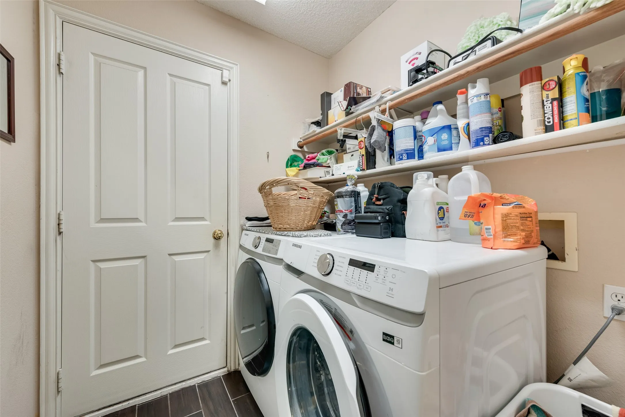 Dedicated laundry area featuring wood-finish flooring, light-toned walls, and a convenient white panel door