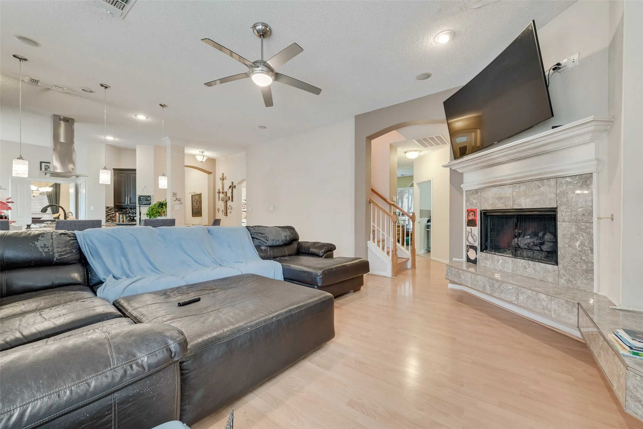 Living area featuring light wood-finish flooring, a ceiling fan, and recessed lighting