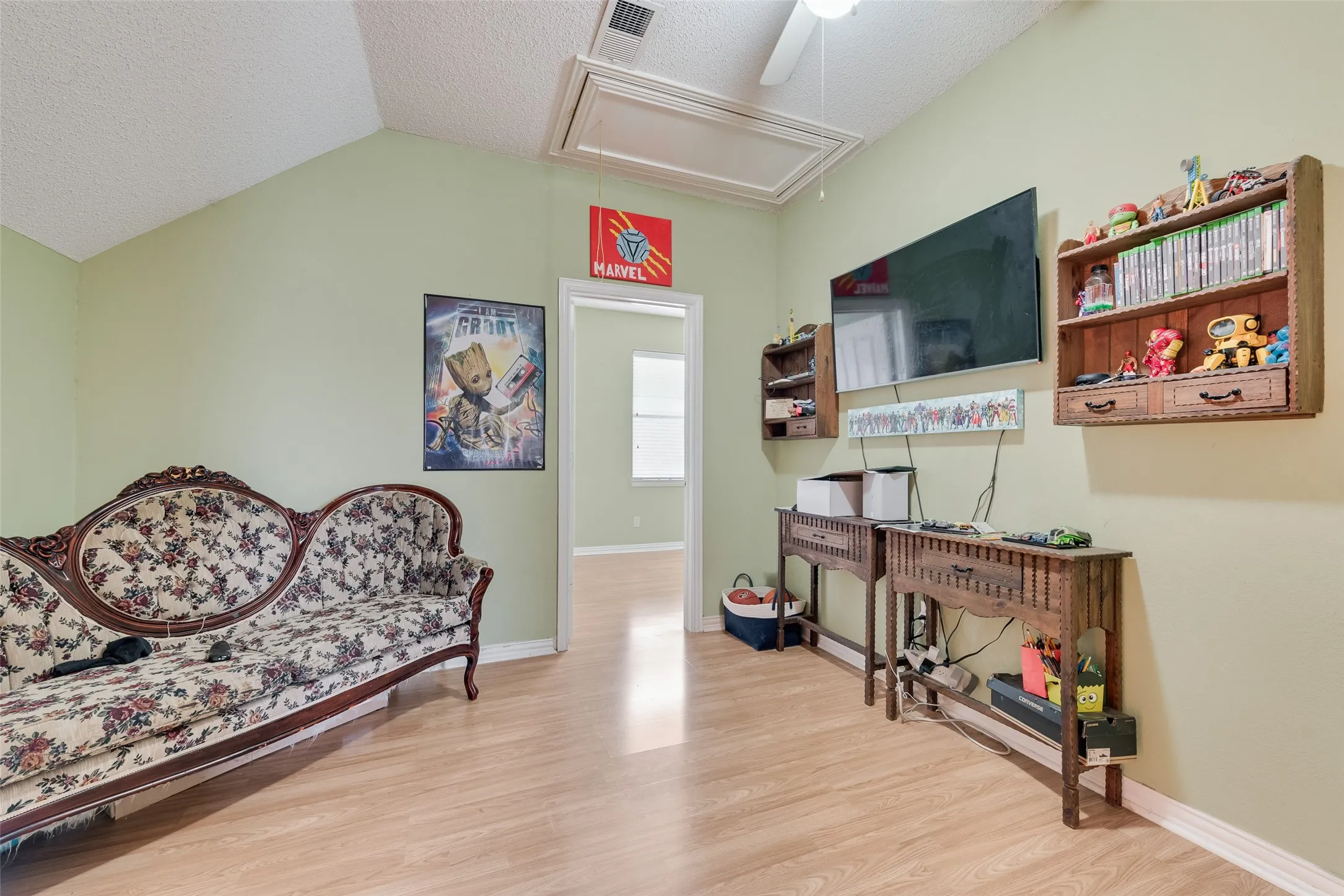 Vaulted ceiling room featuring light wood-finish flooring, a ceiling fan, and a light-colored wall paint