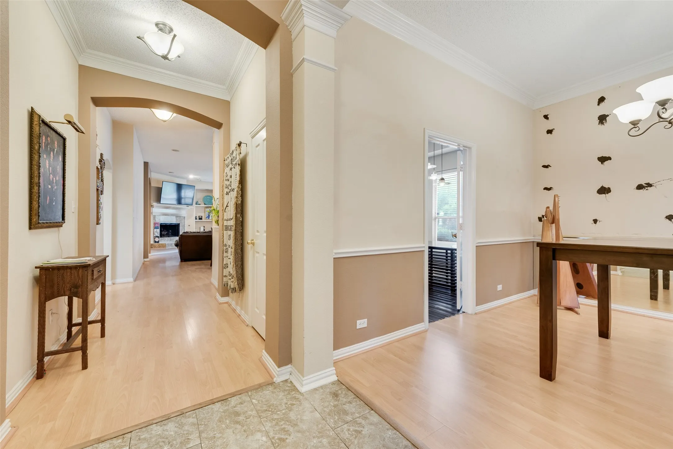 Expansive entryway featuring light wood-finish flooring, an arched doorway, and crown molding
