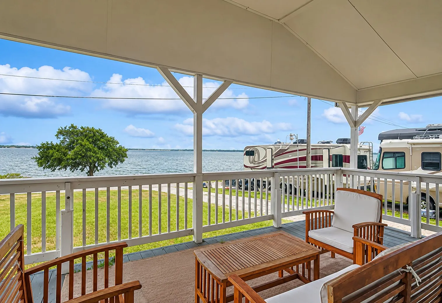 Spacious covered porch featuring a painted wood-finish deck, white railing, and open water scenery