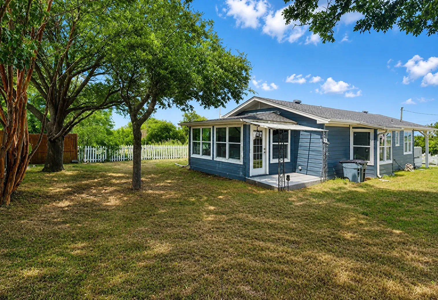 Blue siding exterior with a white trim sunroom, featuring multiple large windows