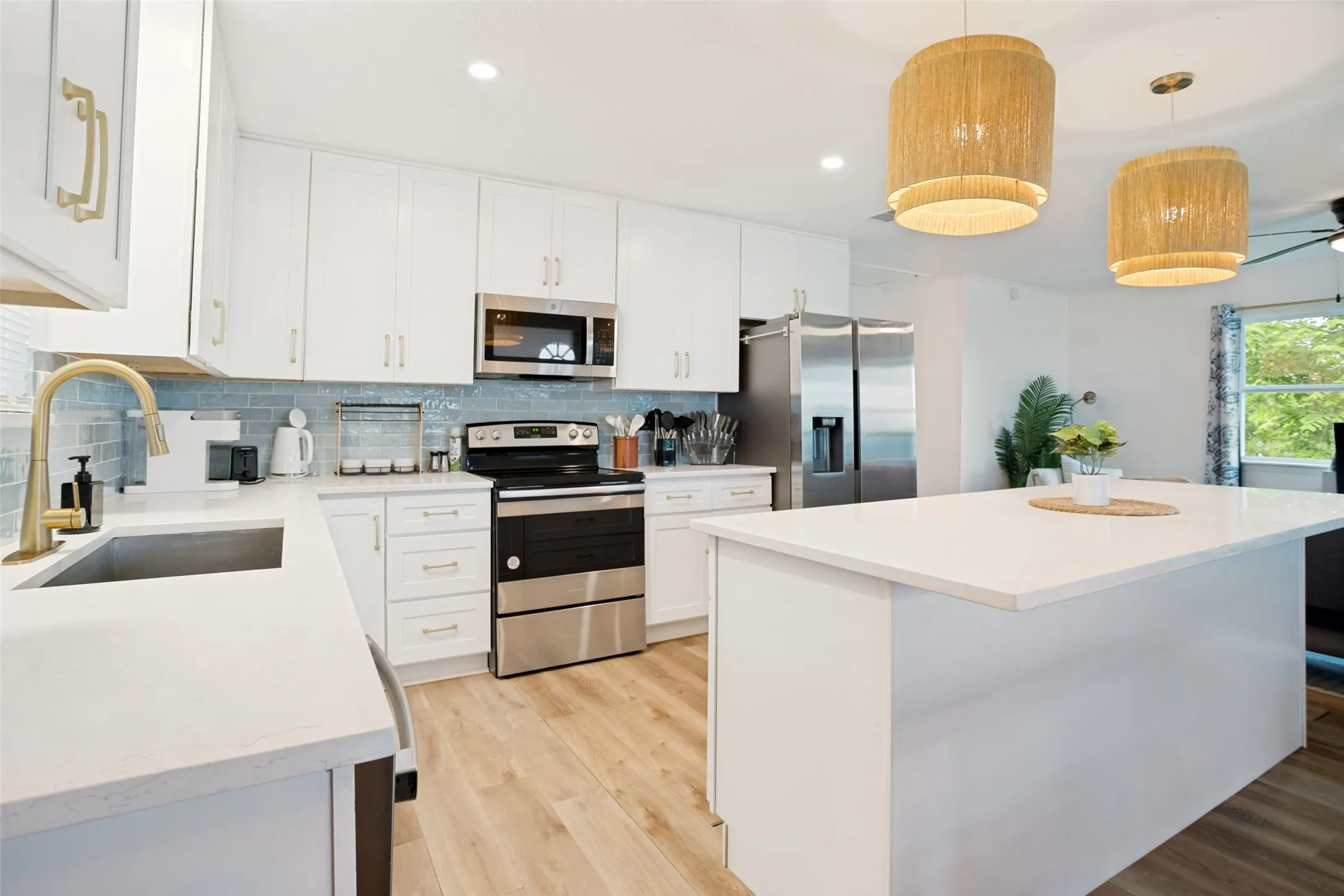 Contemporary kitchen featuring white cabinetry, light wood-finish flooring, and a spacious island with a white countertop