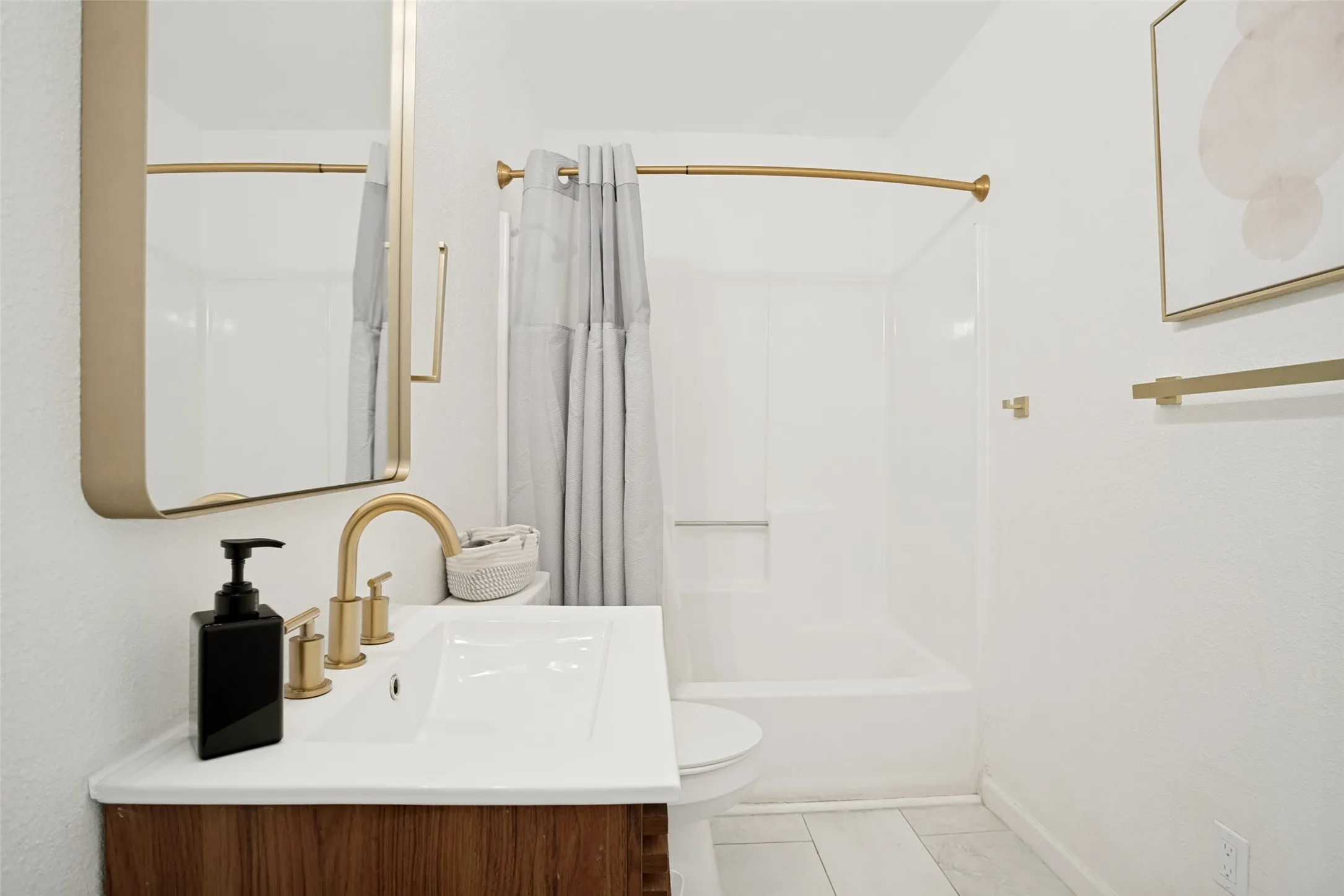 Bathroom featuring a wood-finish vanity with an integrated sink and gold-tone faucet