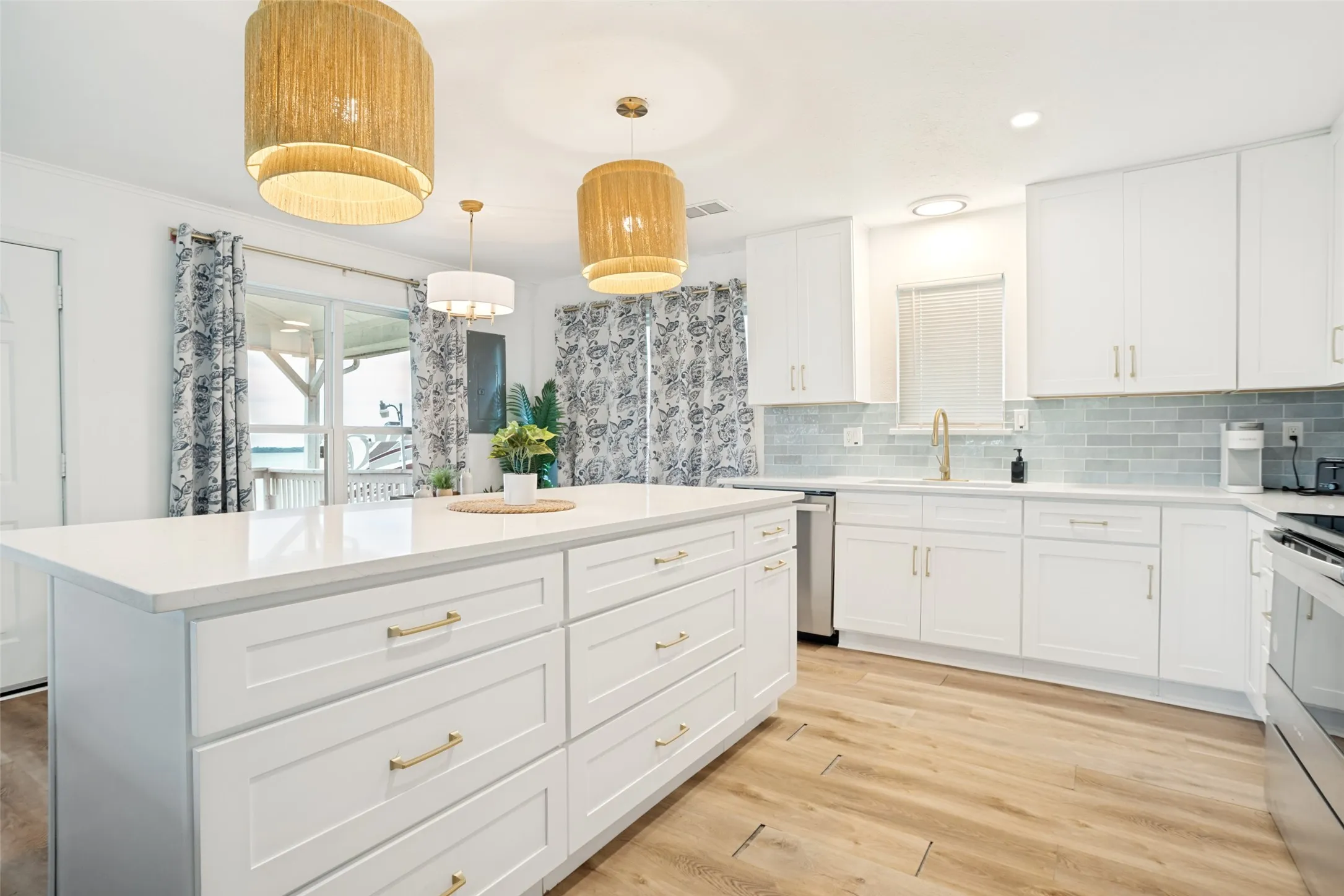 Spacious kitchen featuring an expansive center island with white shaker cabinetry, gold hardware, and a white countertop