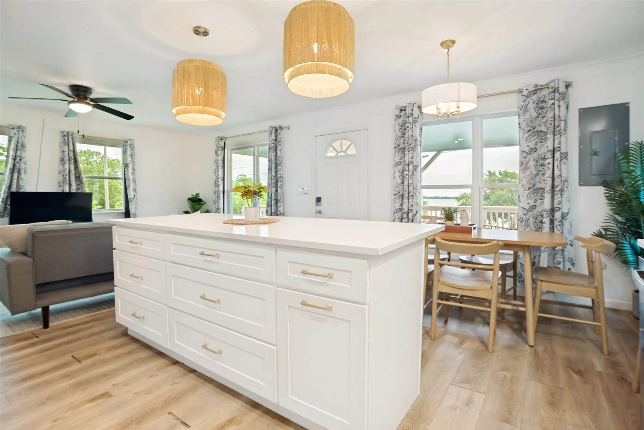 Kitchen island with white shaker cabinetry, gold-tone hardware, and a light-toned countertop