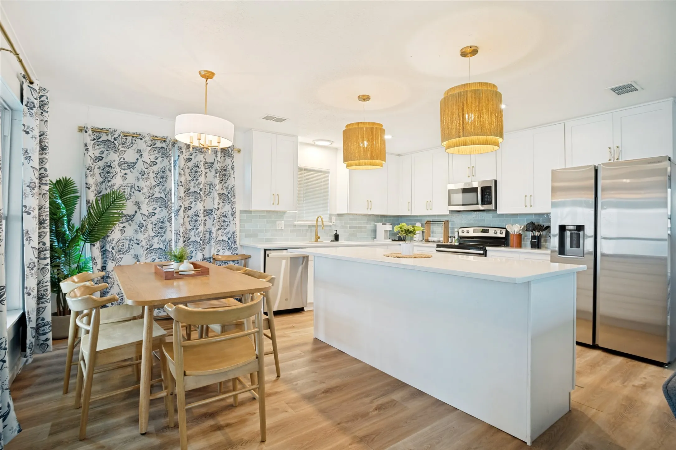 Contemporary kitchen featuring white cabinetry, a large kitchen island with a white countertop, and stainless steel appliances